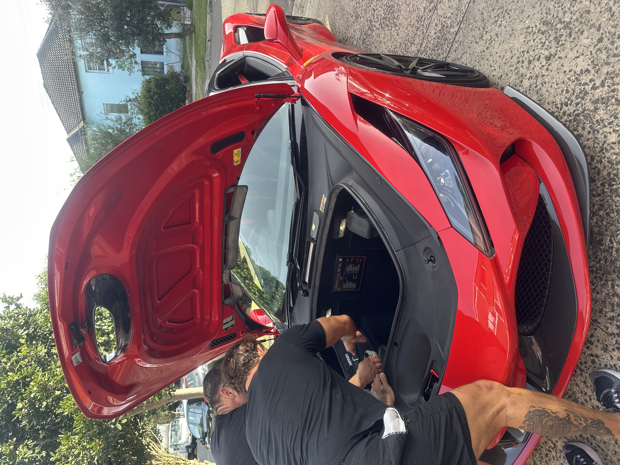 Two men service red Ferrari's front trunk in Maroubra