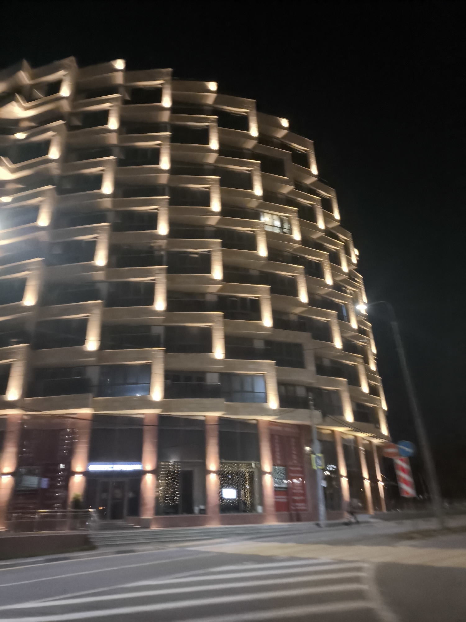 City lights and modern architecture at night from a moving vehicle
