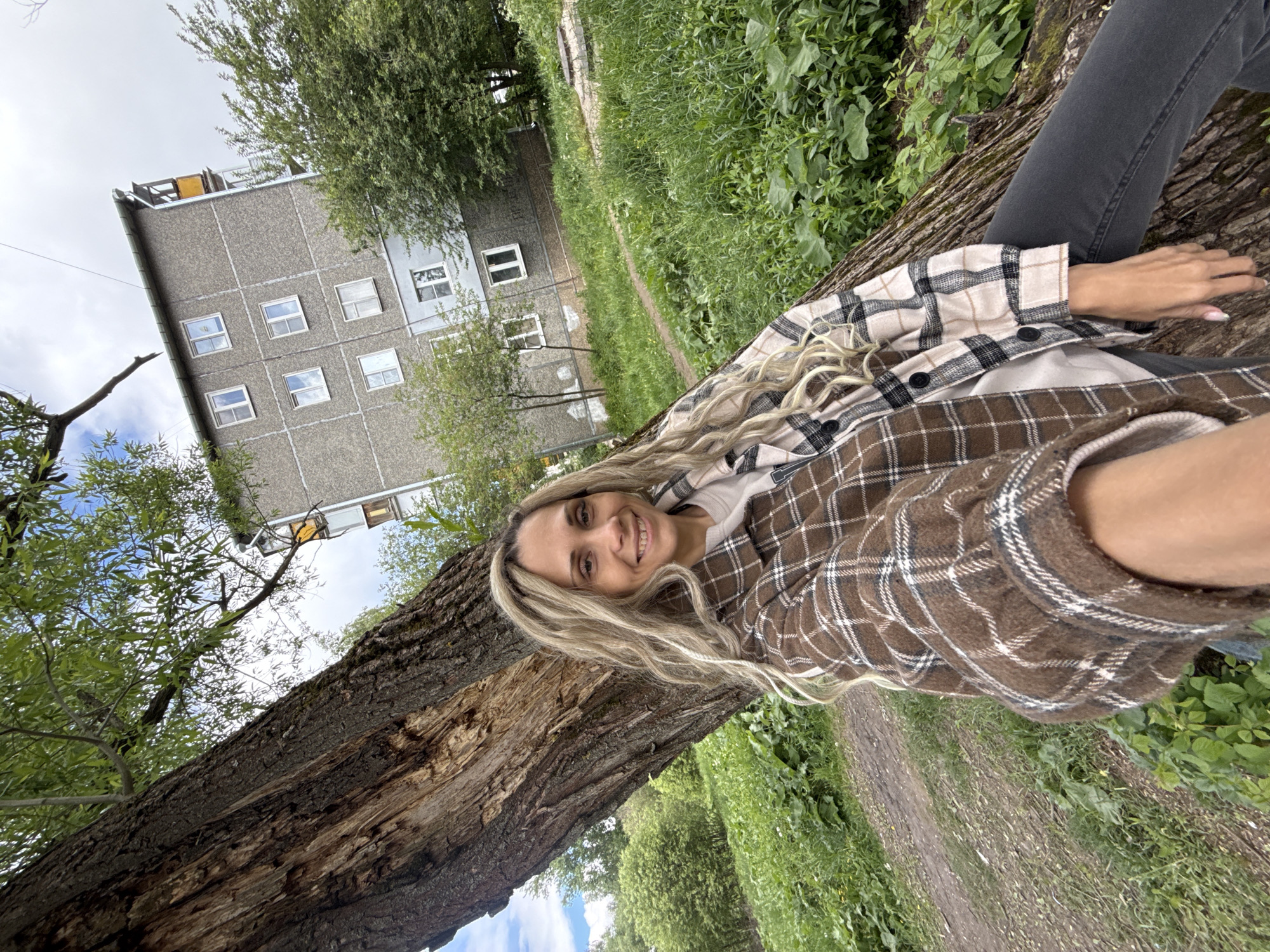 Woman rests on fallen tree in Russian residential area