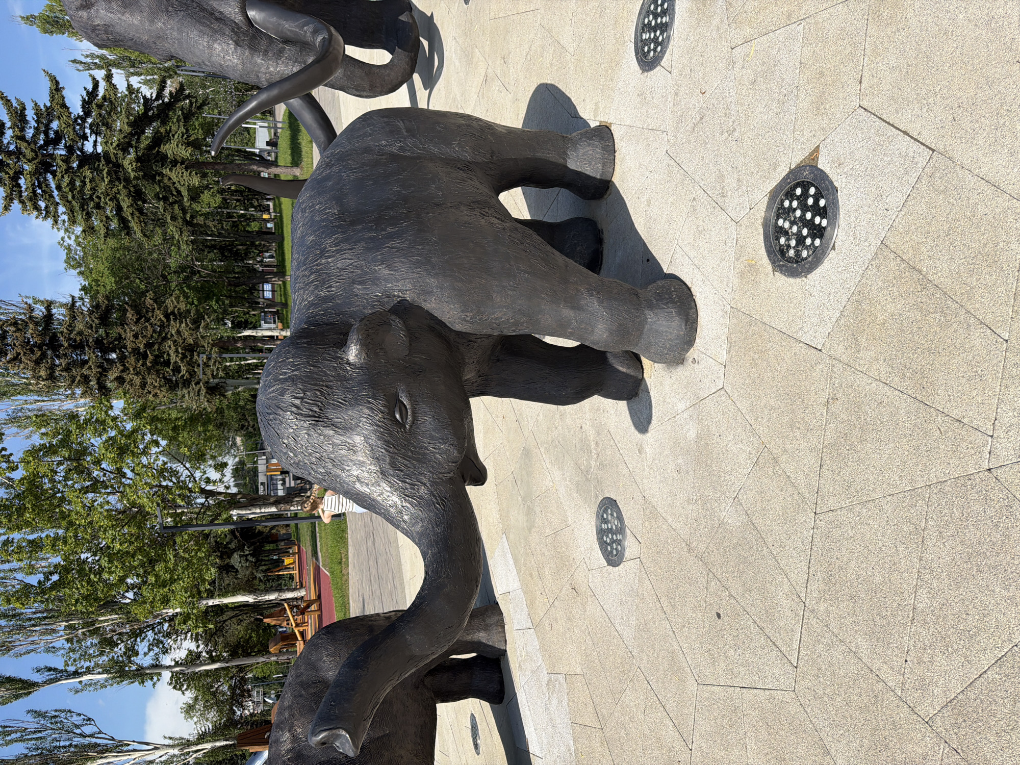 Child's morning park visit documented with sculptures, playground, flowers