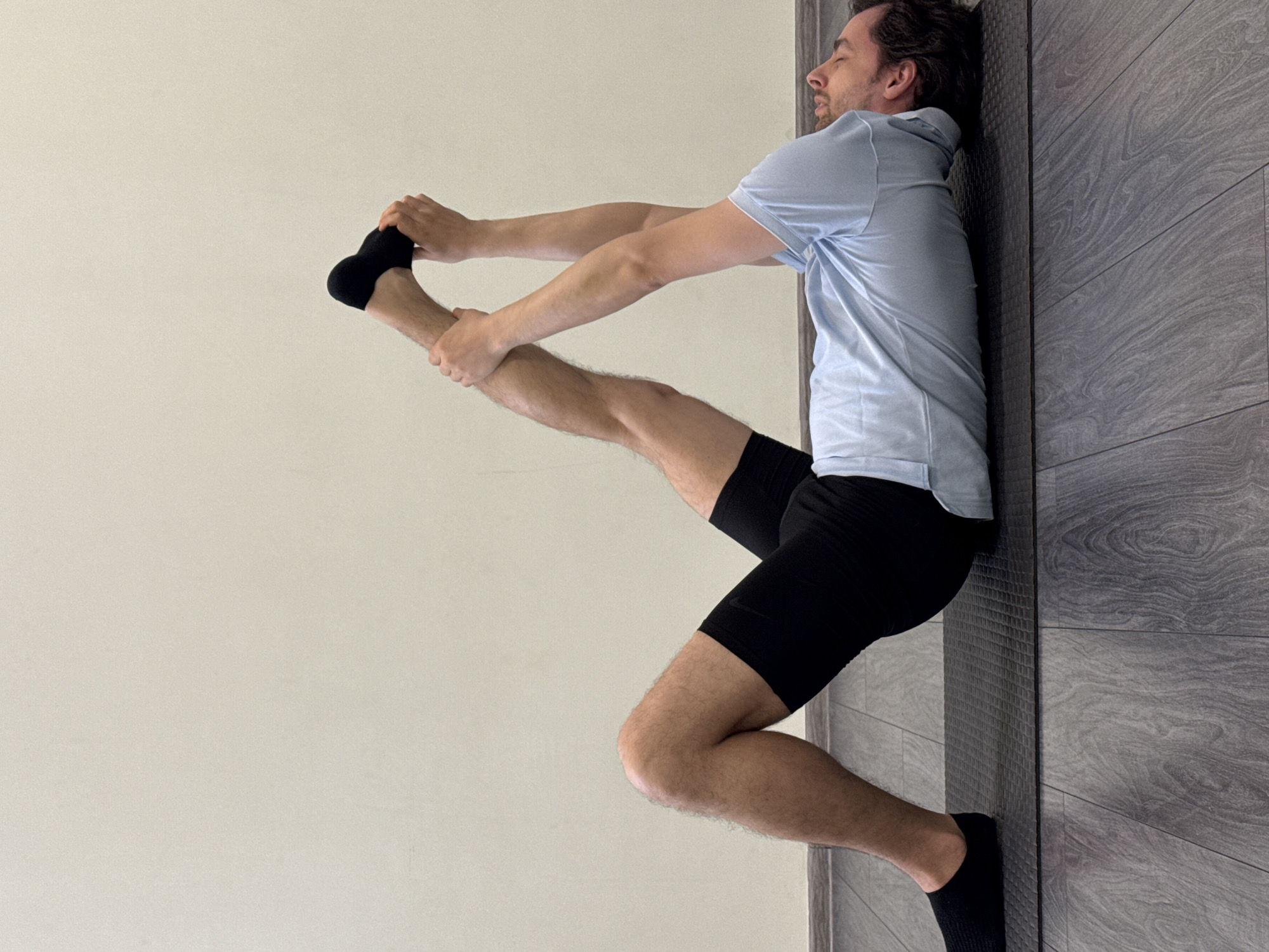 Man performs morning stretching routine against wall