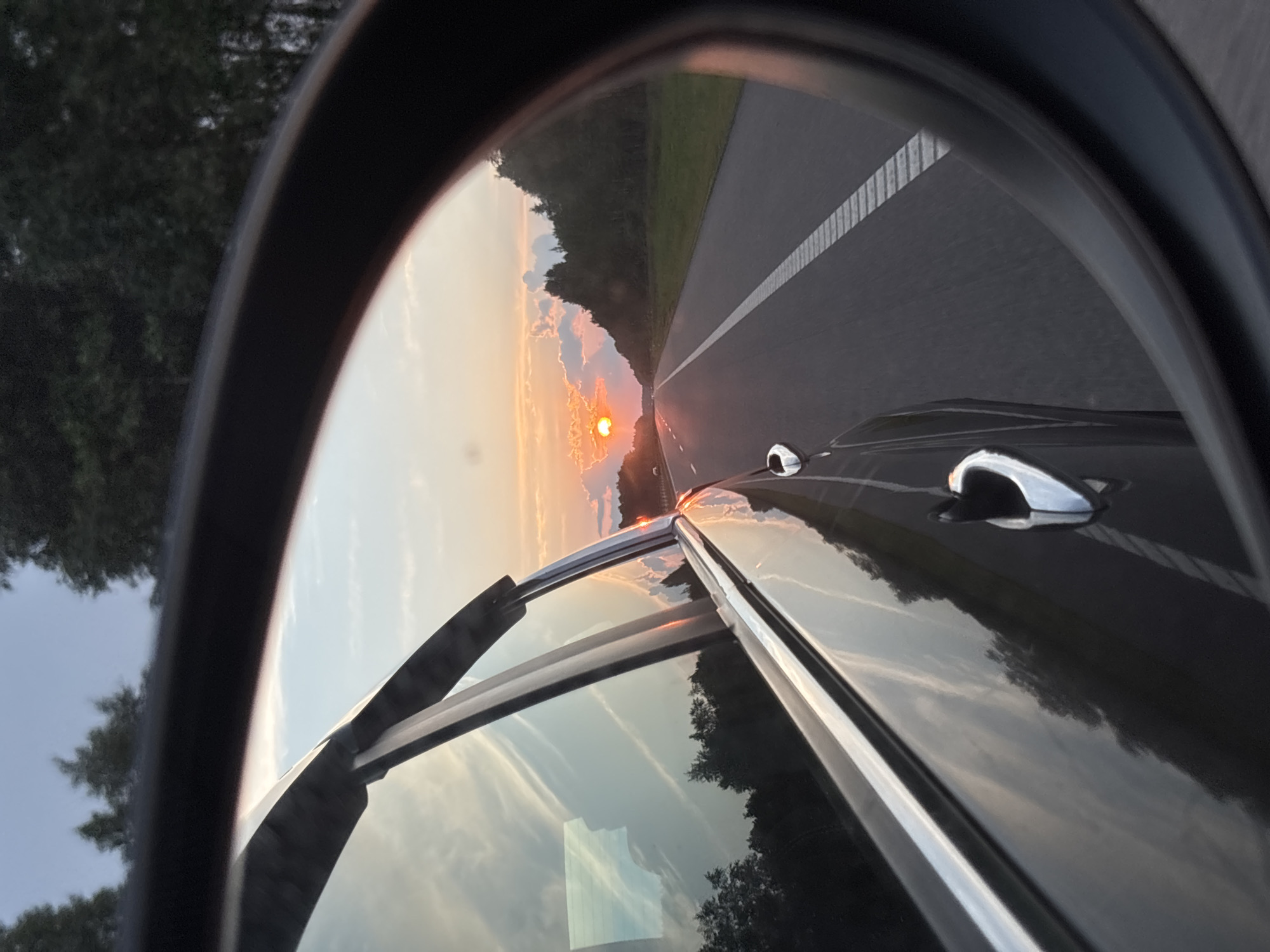 Sunset reflected in a rearview mirror on a Belarus highway