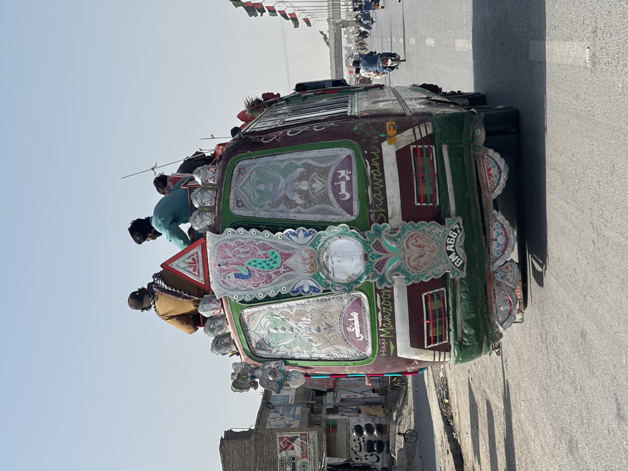 Decorated bus with roof passengers travels through Quetta