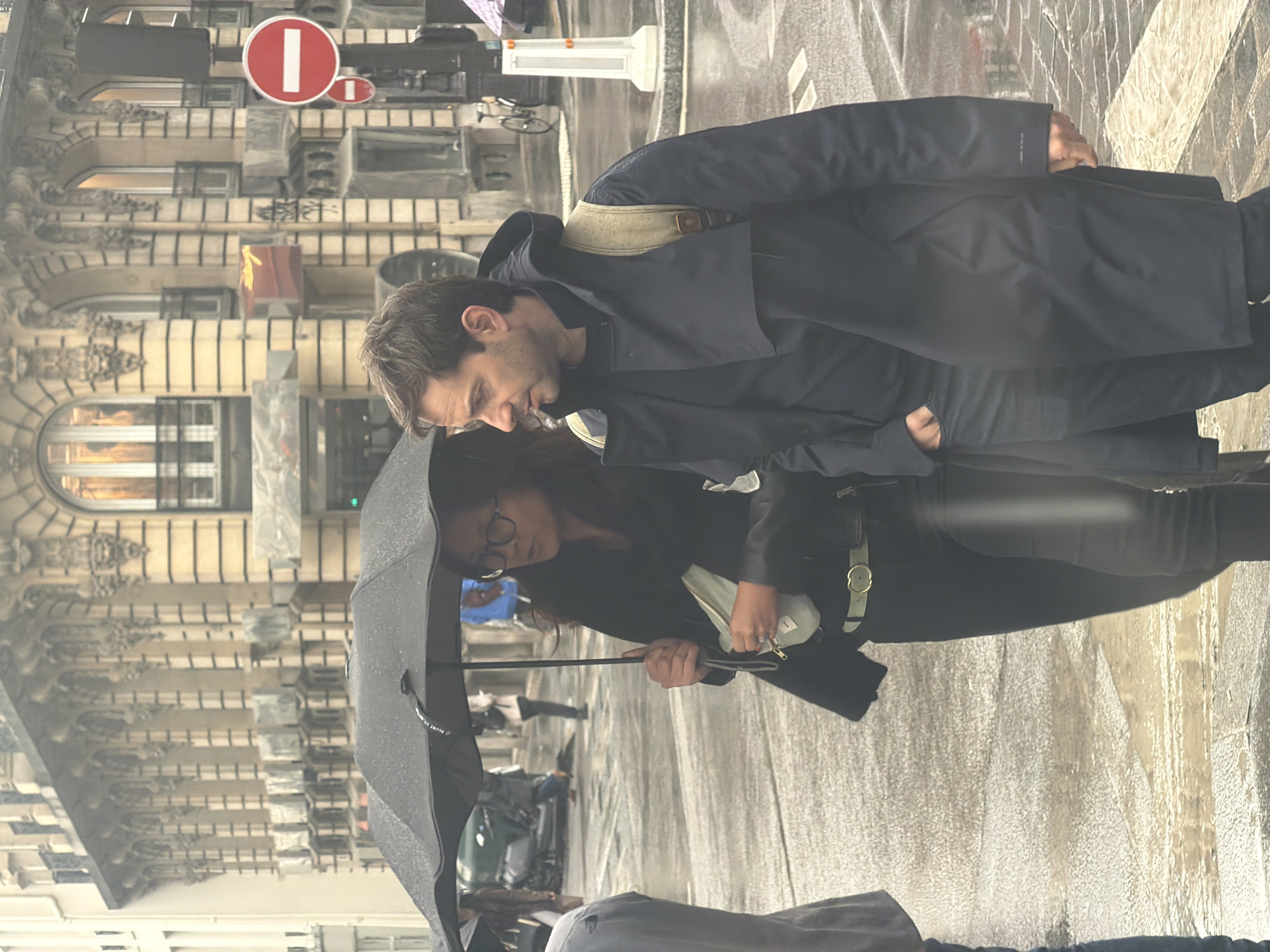 Parisians navigate afternoon rainstorm with umbrellas near city center