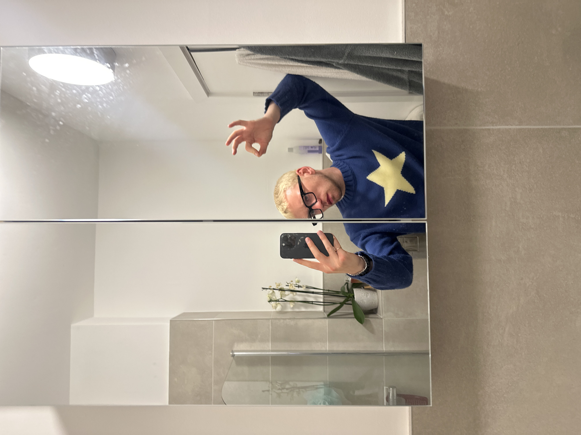 Person takes bathroom mirror selfie in star-patterned sweater