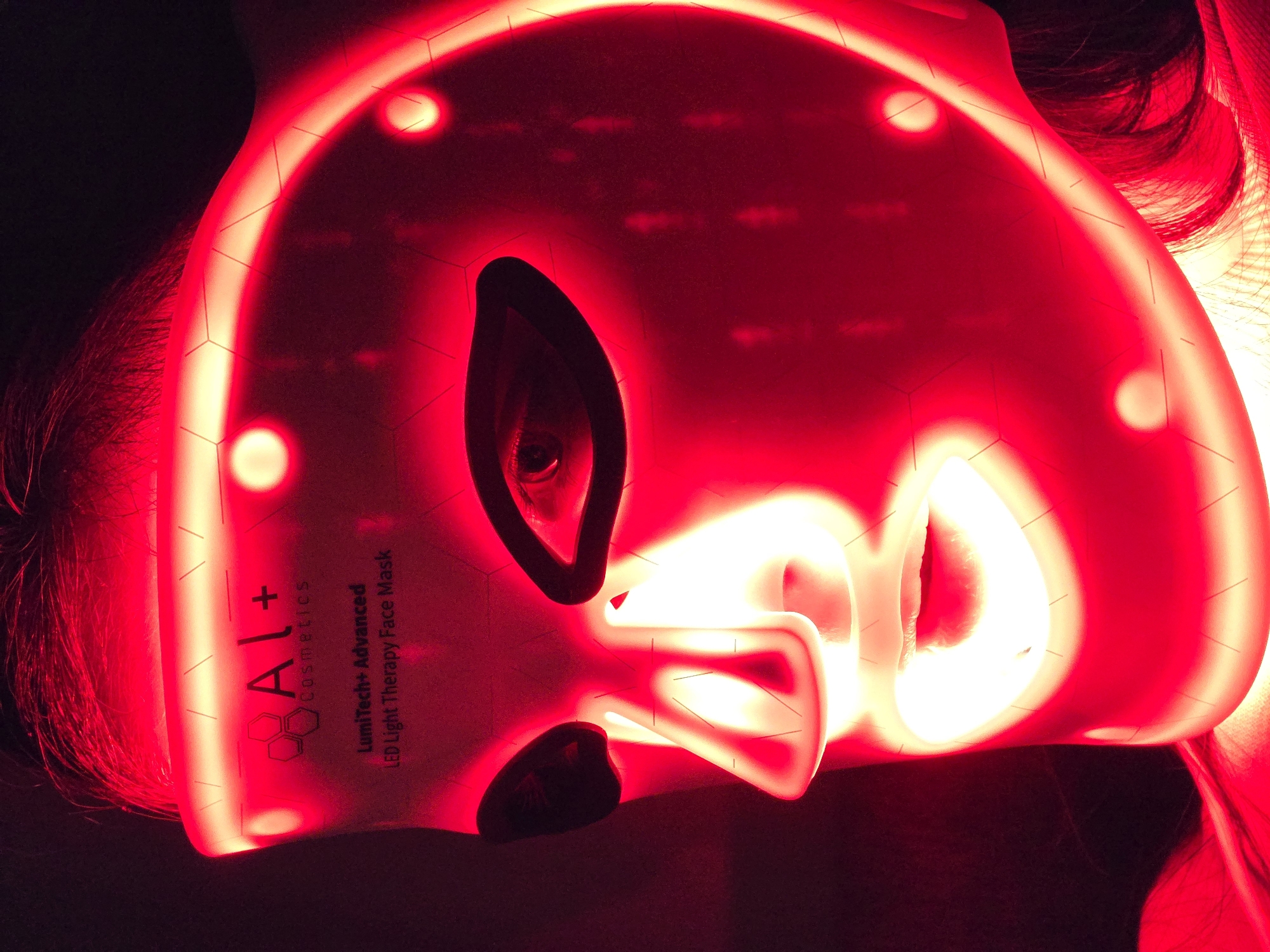 Person Uses Red LED Light Therapy Mask in Dark Room