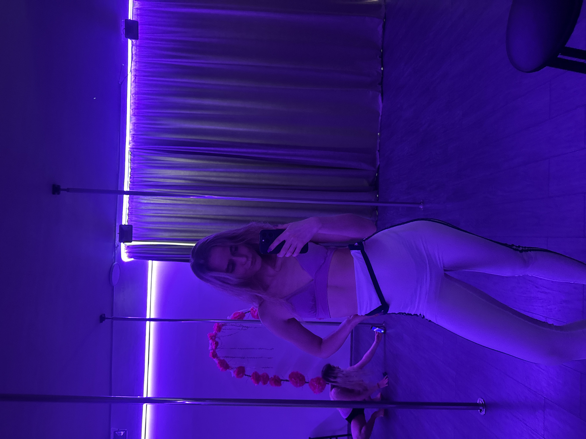 Pole fitness class documented at purple-lit studio
