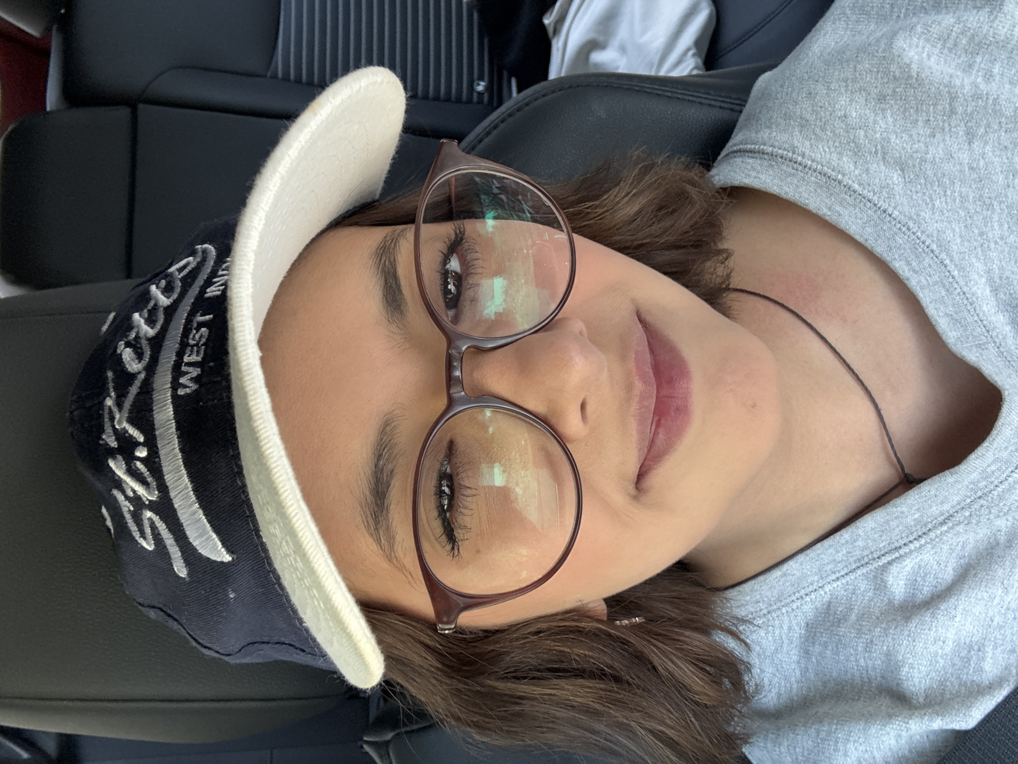 Person rests in vehicle wearing St. Kitts cap in Puebla
