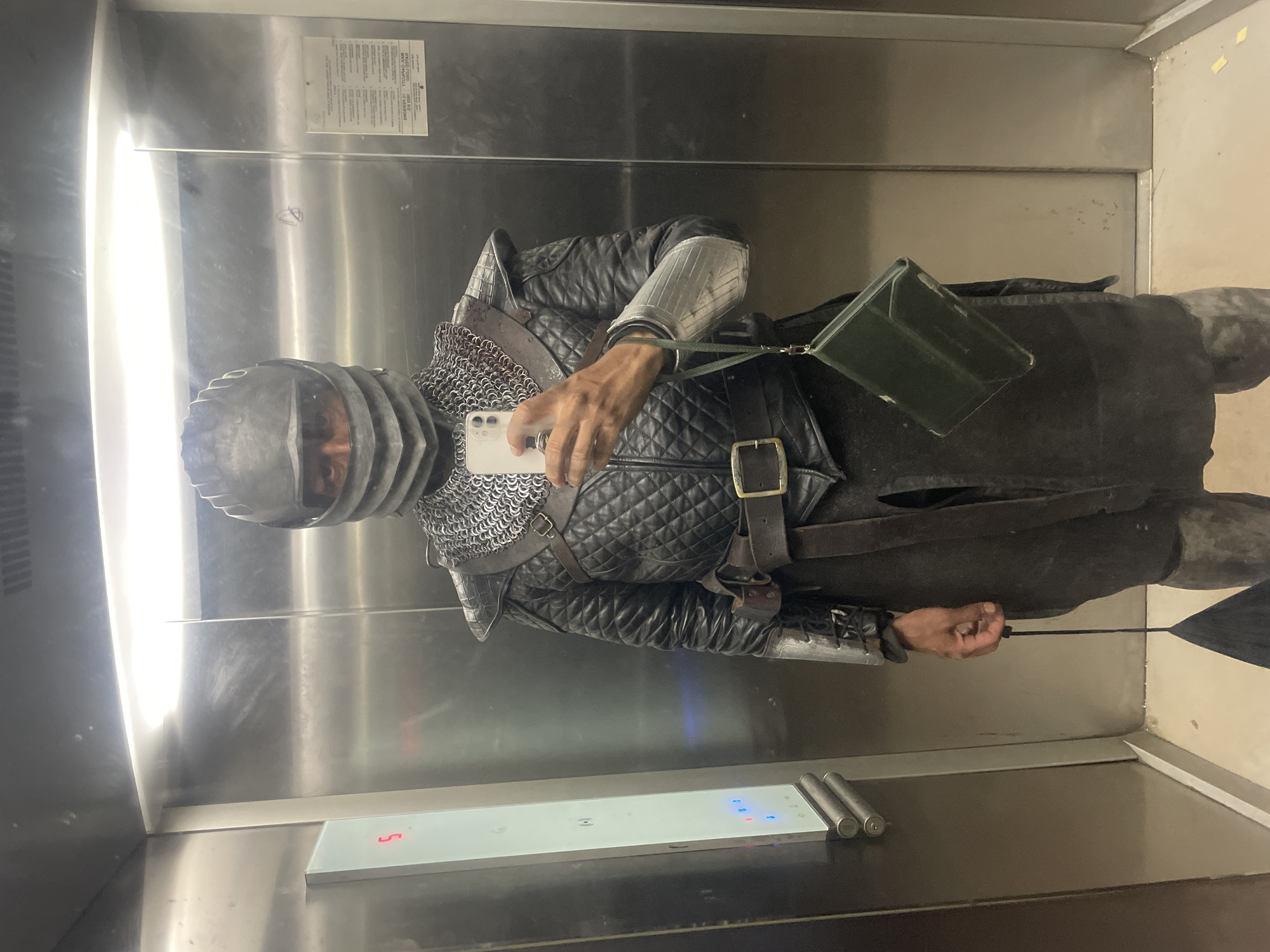 Medieval armored figure takes elevator selfie with smartphone