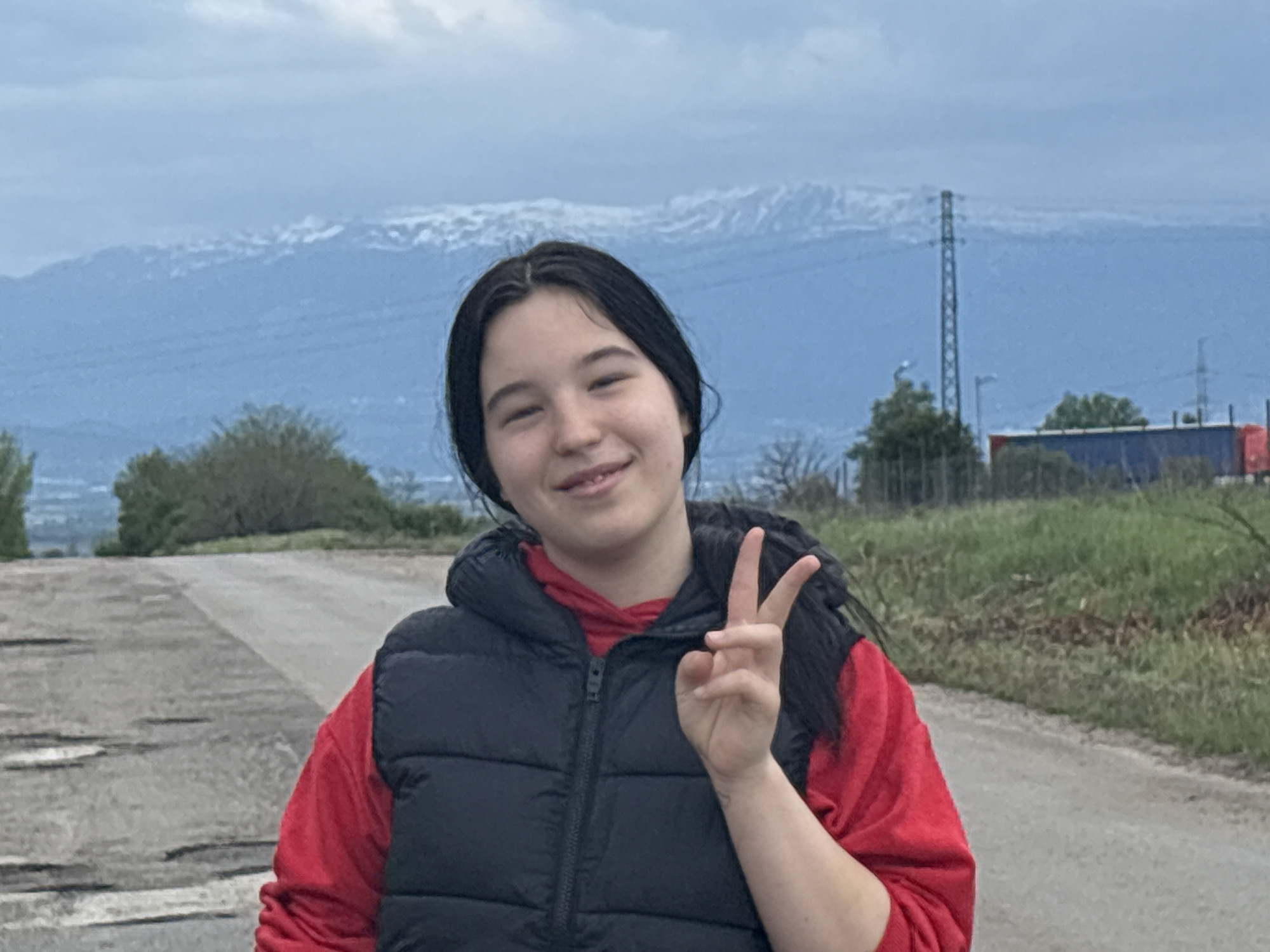 Woman makes peace sign on cracked road in Bulgarian village