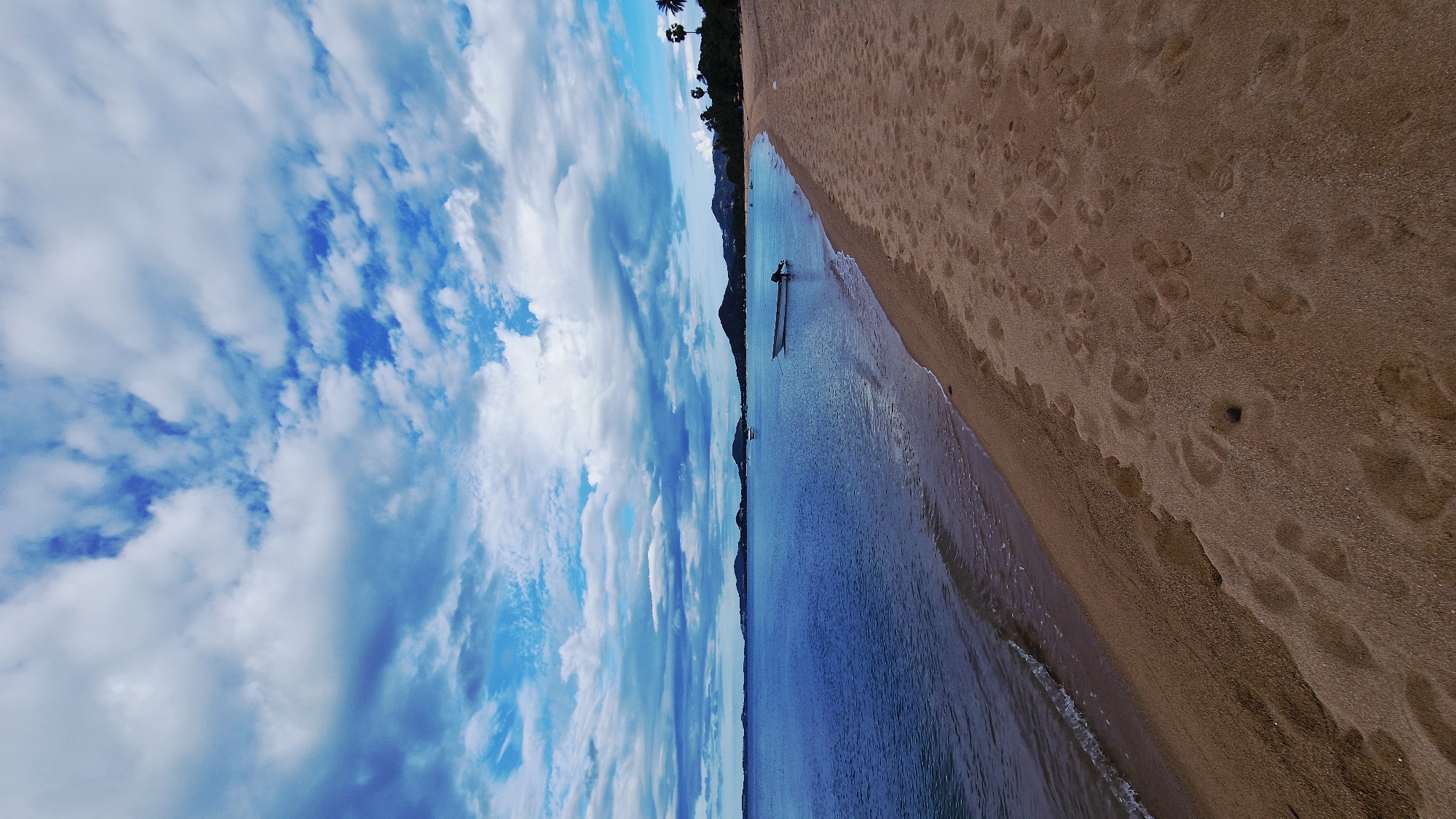 Beach scene documented in Baan Tai with footprints, waves