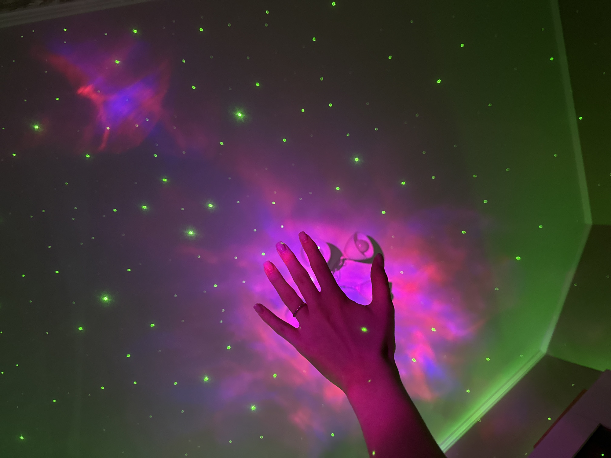 Cozy bedroom setup with galaxy projector, moon lamp, and skincare