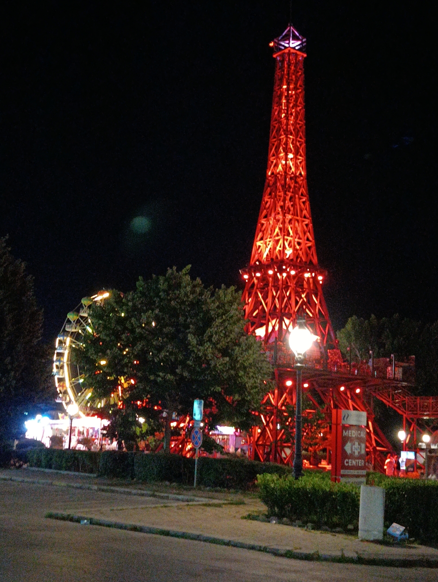 Red Eiffel Tower replica glows at a nighttime fairground