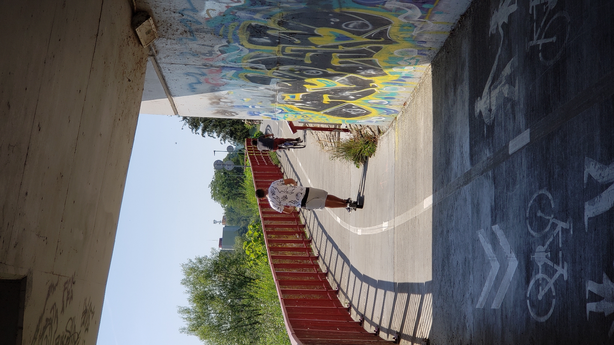 Graffiti-covered bridge frames a bike path along the Torysa River