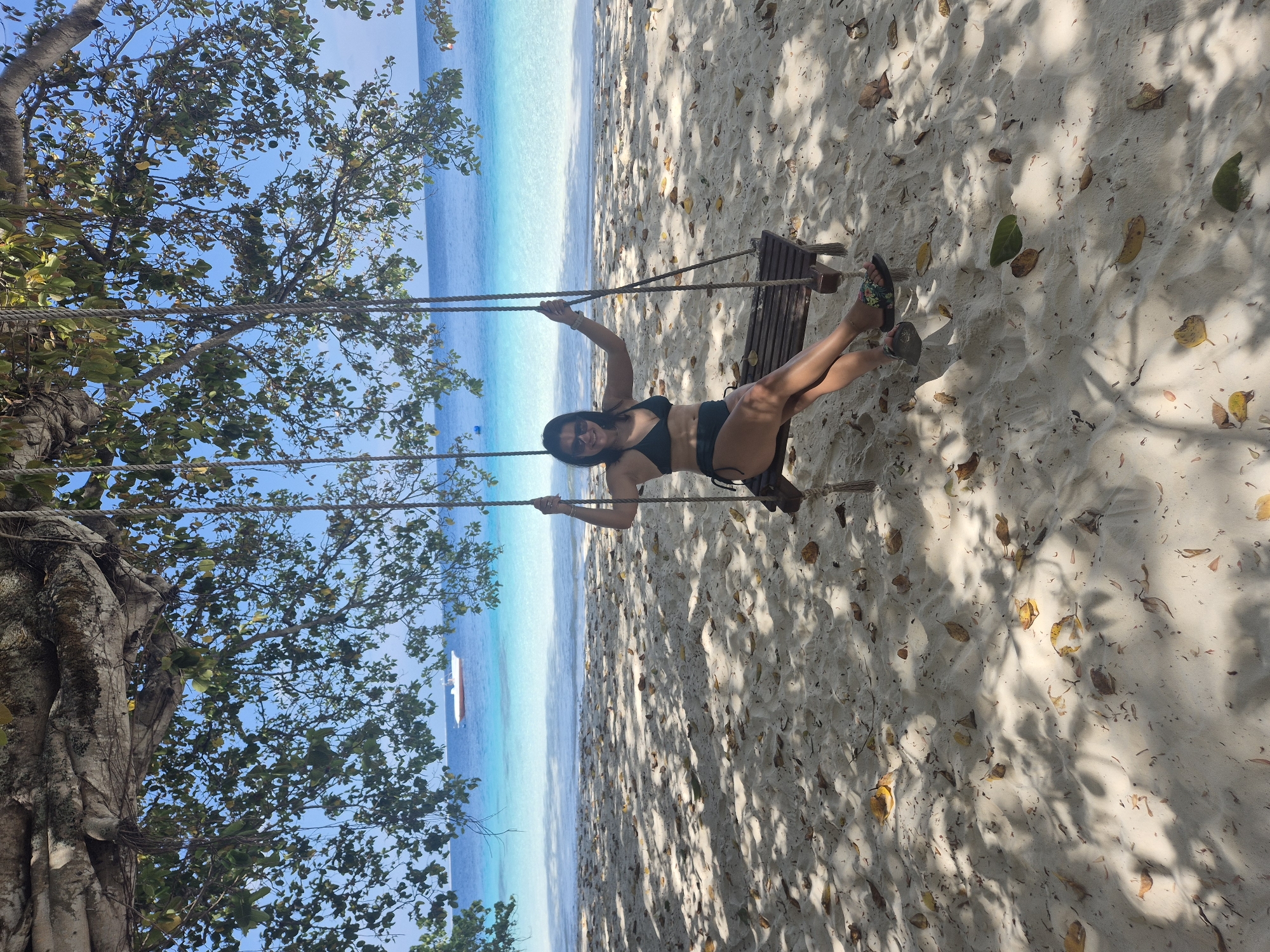 Woman enjoys rope swing at Guraidhoo beach, Maldives