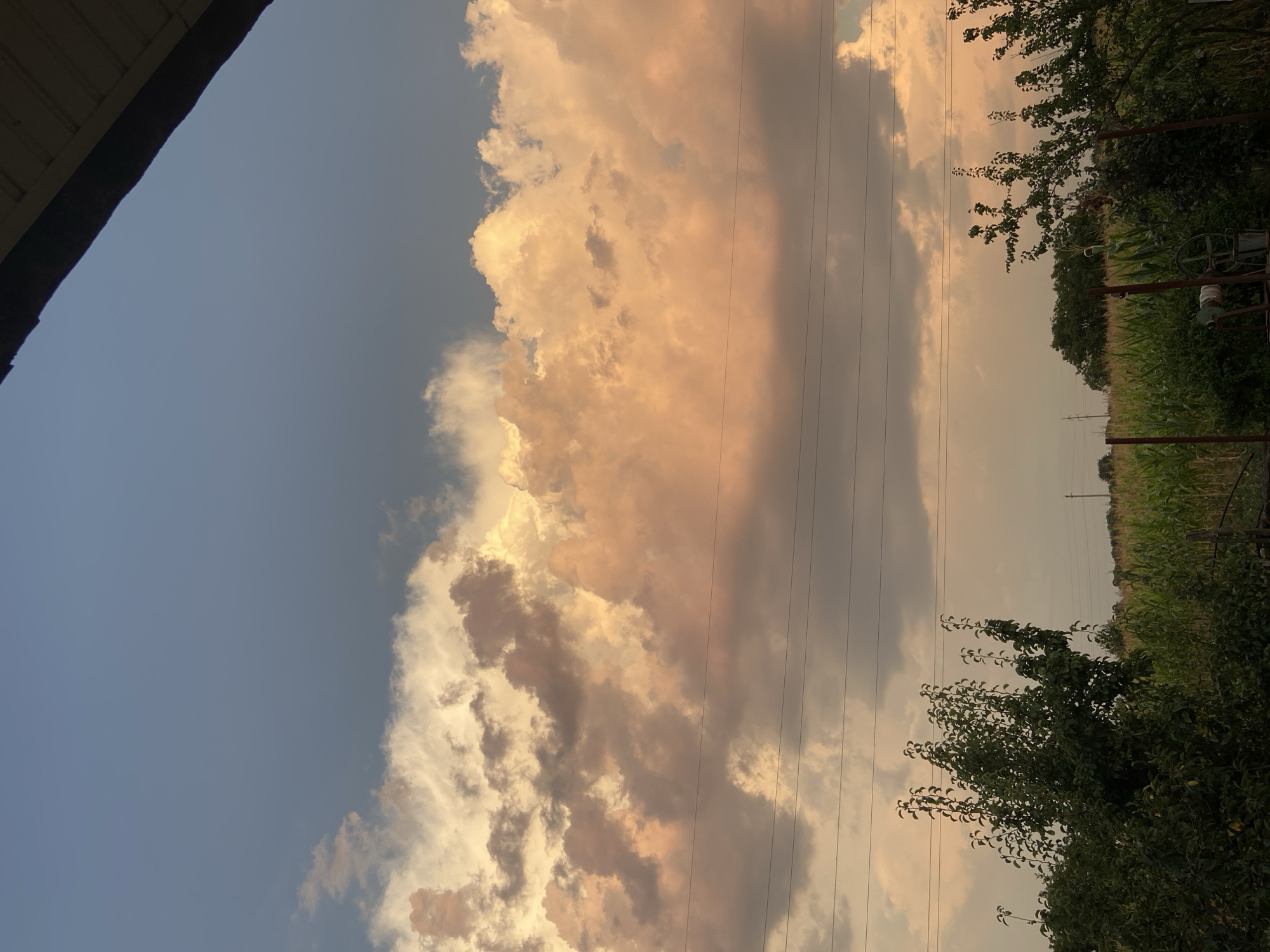 Rural sunset sky, clouds, and a parked car near a fence