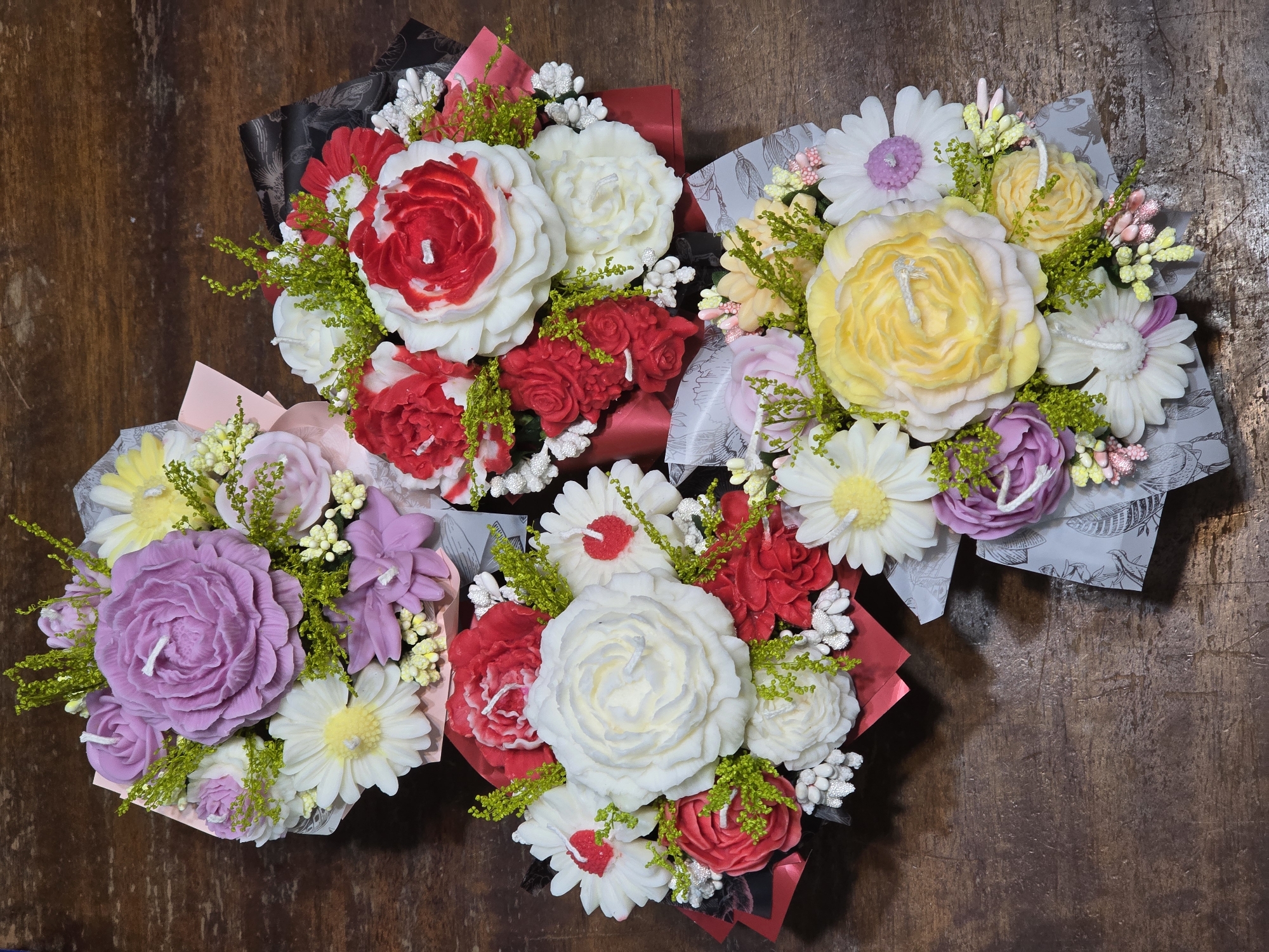 Decorative candle flower bouquets arranged on wooden surface