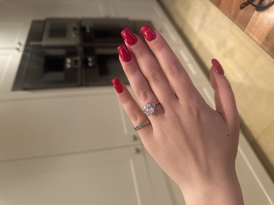 Woman shows off red nails, rings in Swiss kitchen
