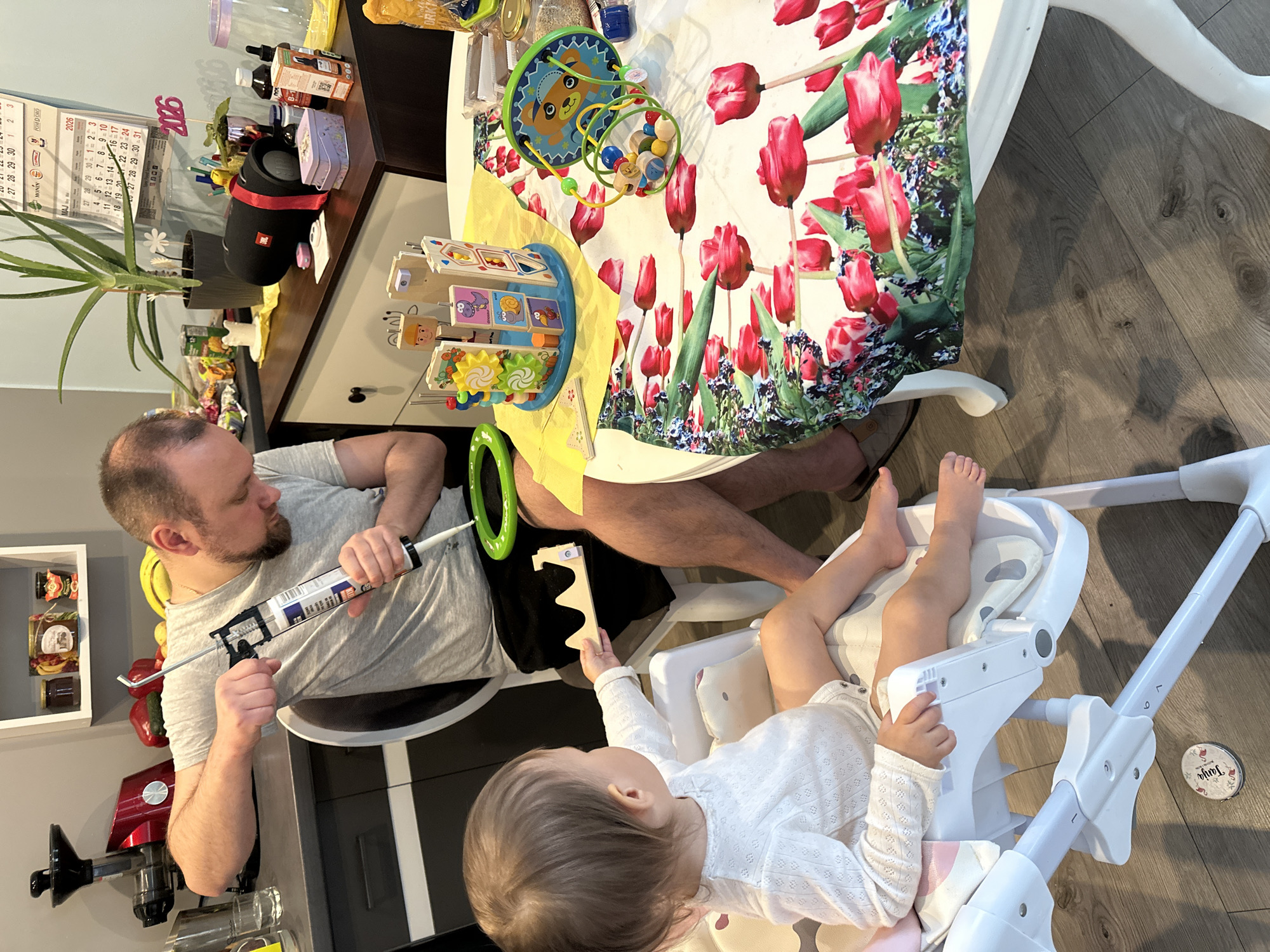 Man repairs wooden toy with caulking gun in Wisła home