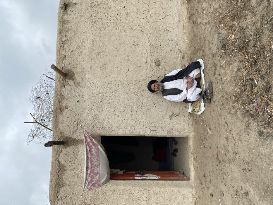 Elderly man rests outside rural home in Kandahar