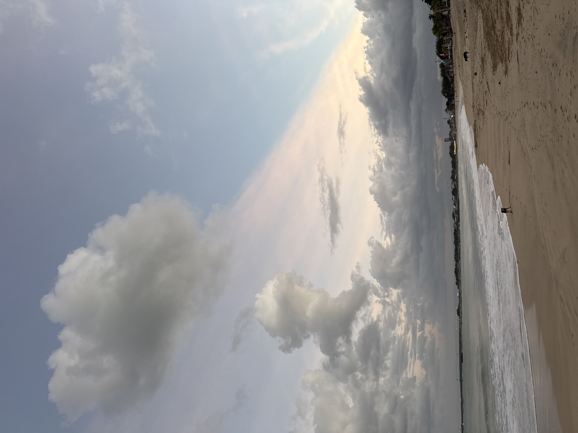 Kuta Beach at golden hour — waves, clouds, and people.
