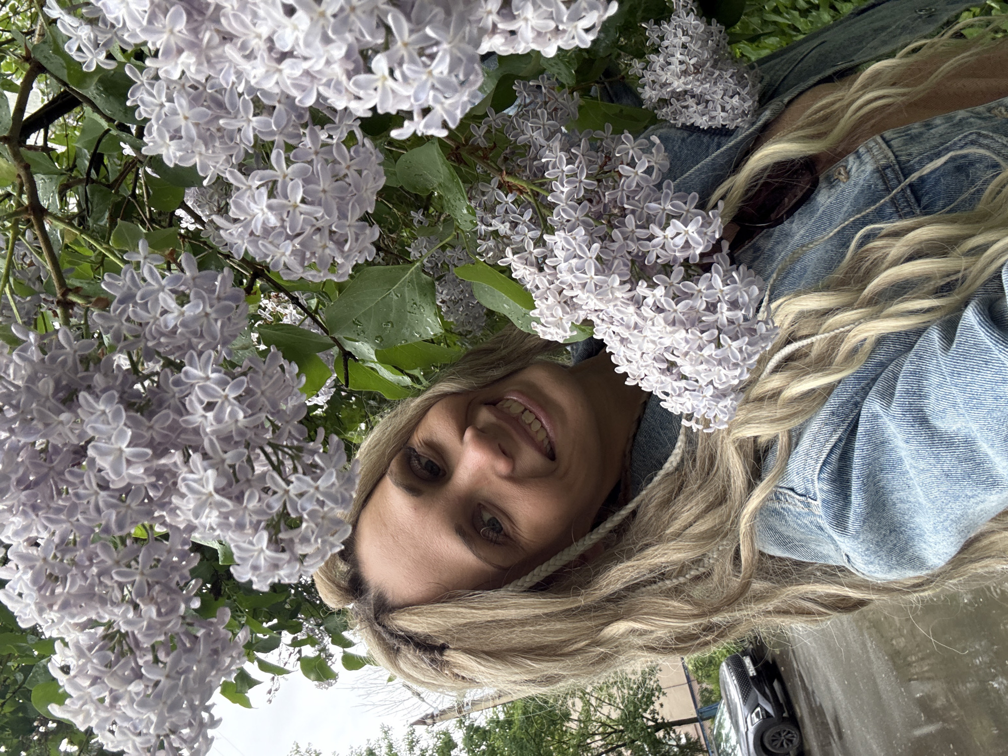 Woman poses with lilac blossoms after rain in Rusanovo