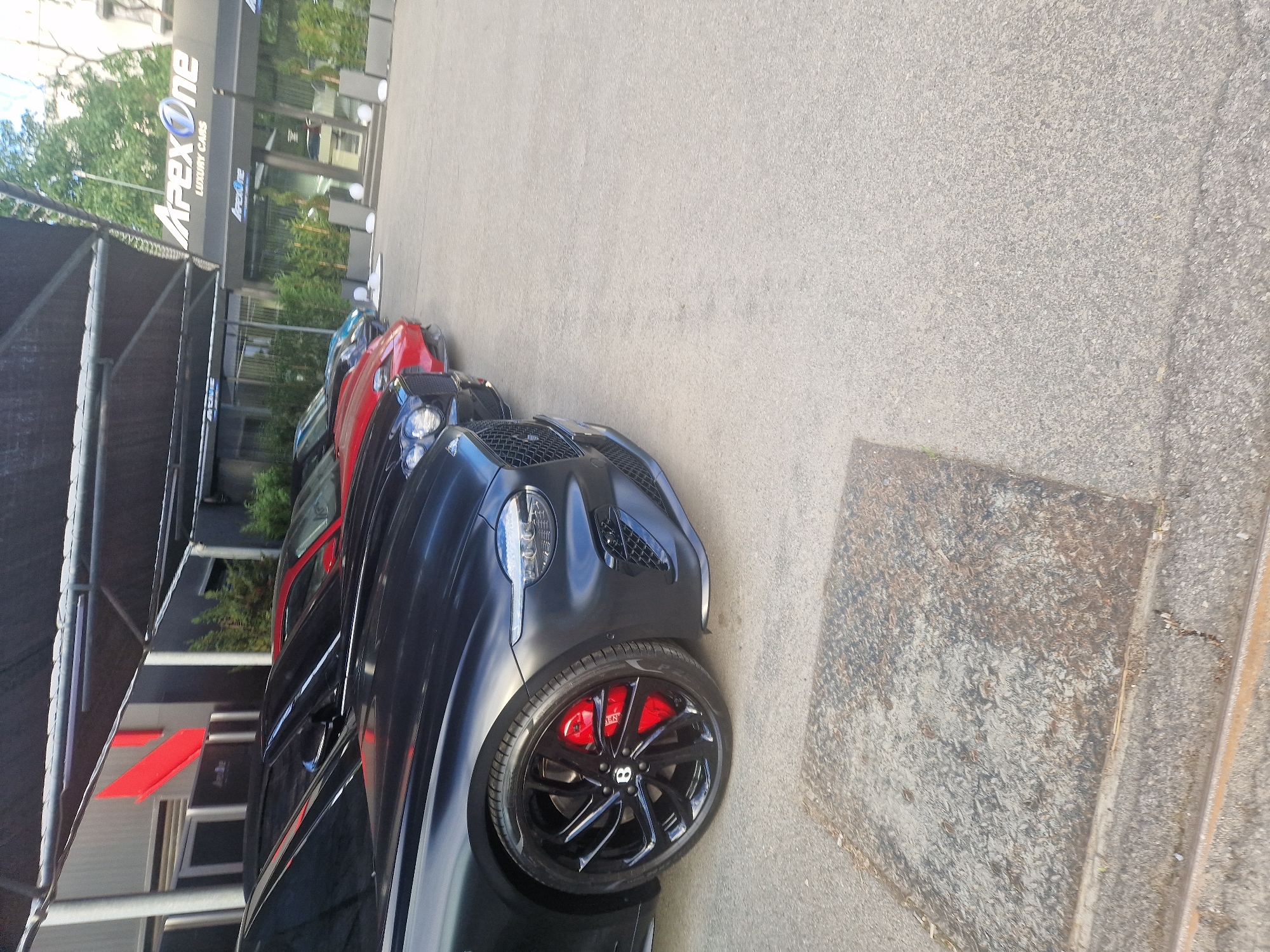 Person visits luxury car dealership, photographed outdoors