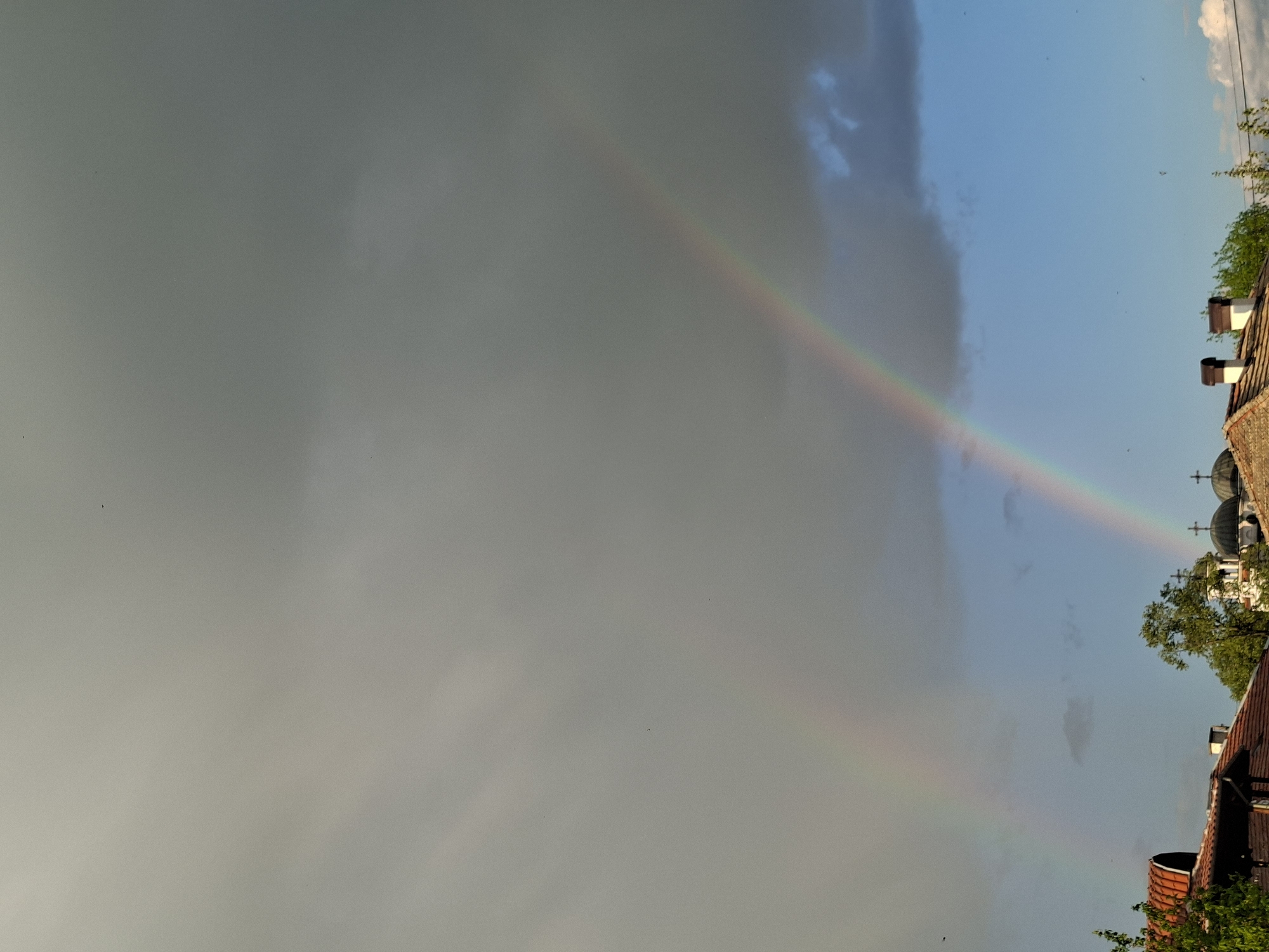 Rainbow appears over domed buildings during afternoon sky clearing