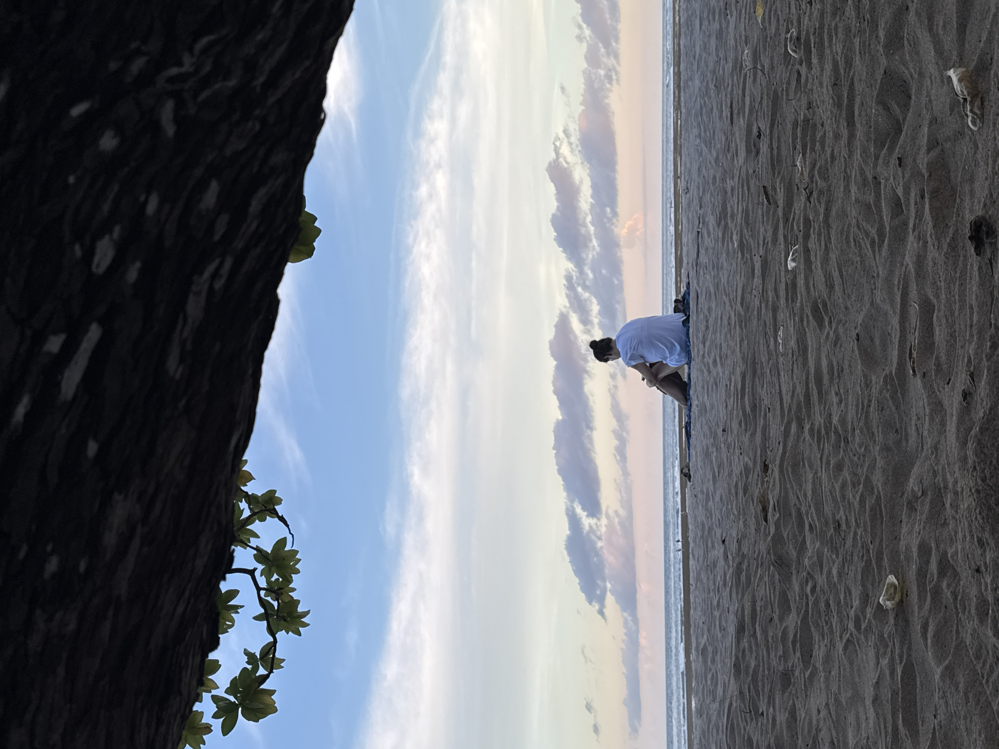 Person sits on Nusa Dua beach under cloudy skies