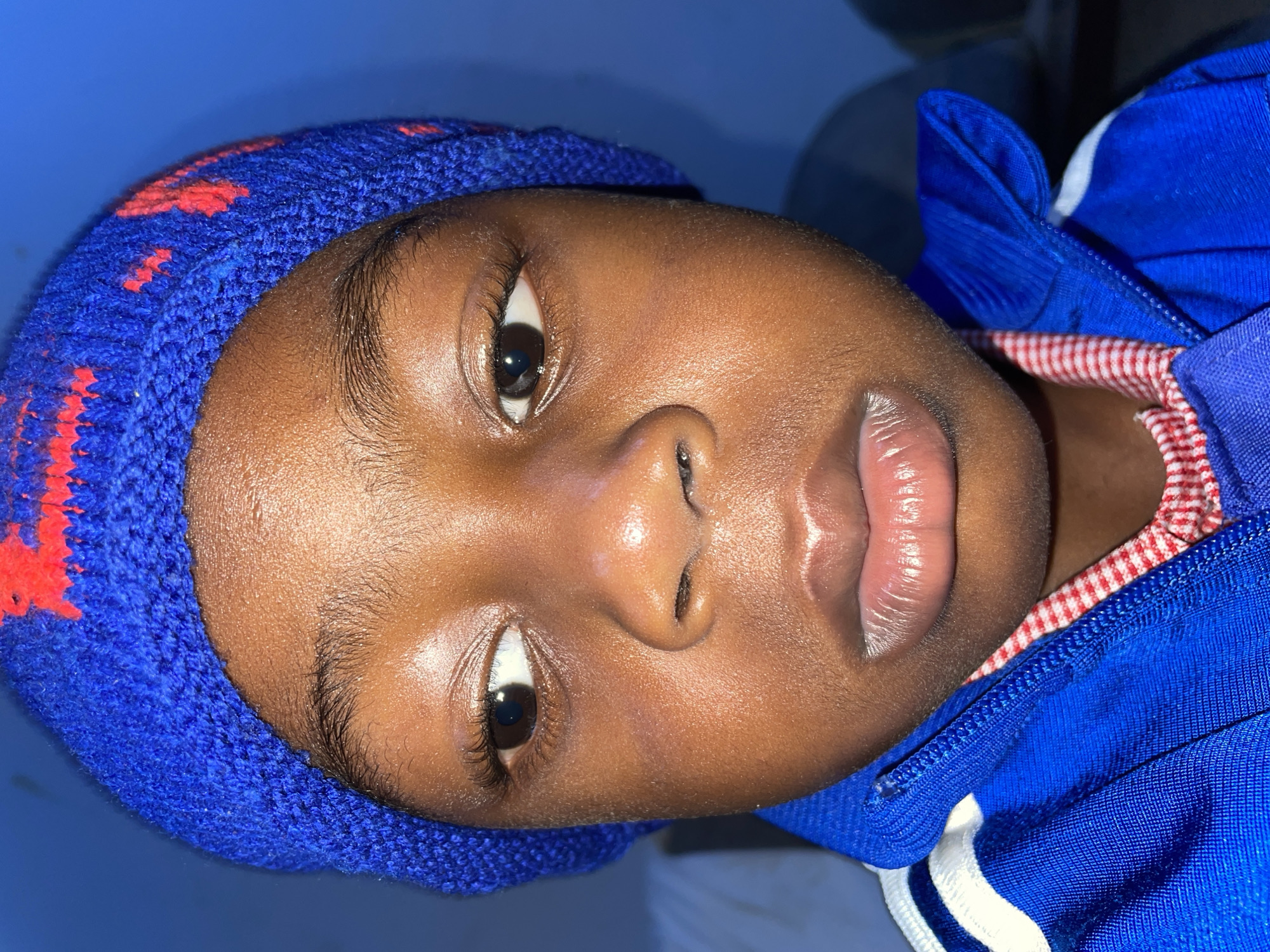 Child in blue tracksuit rests on furniture in Jos