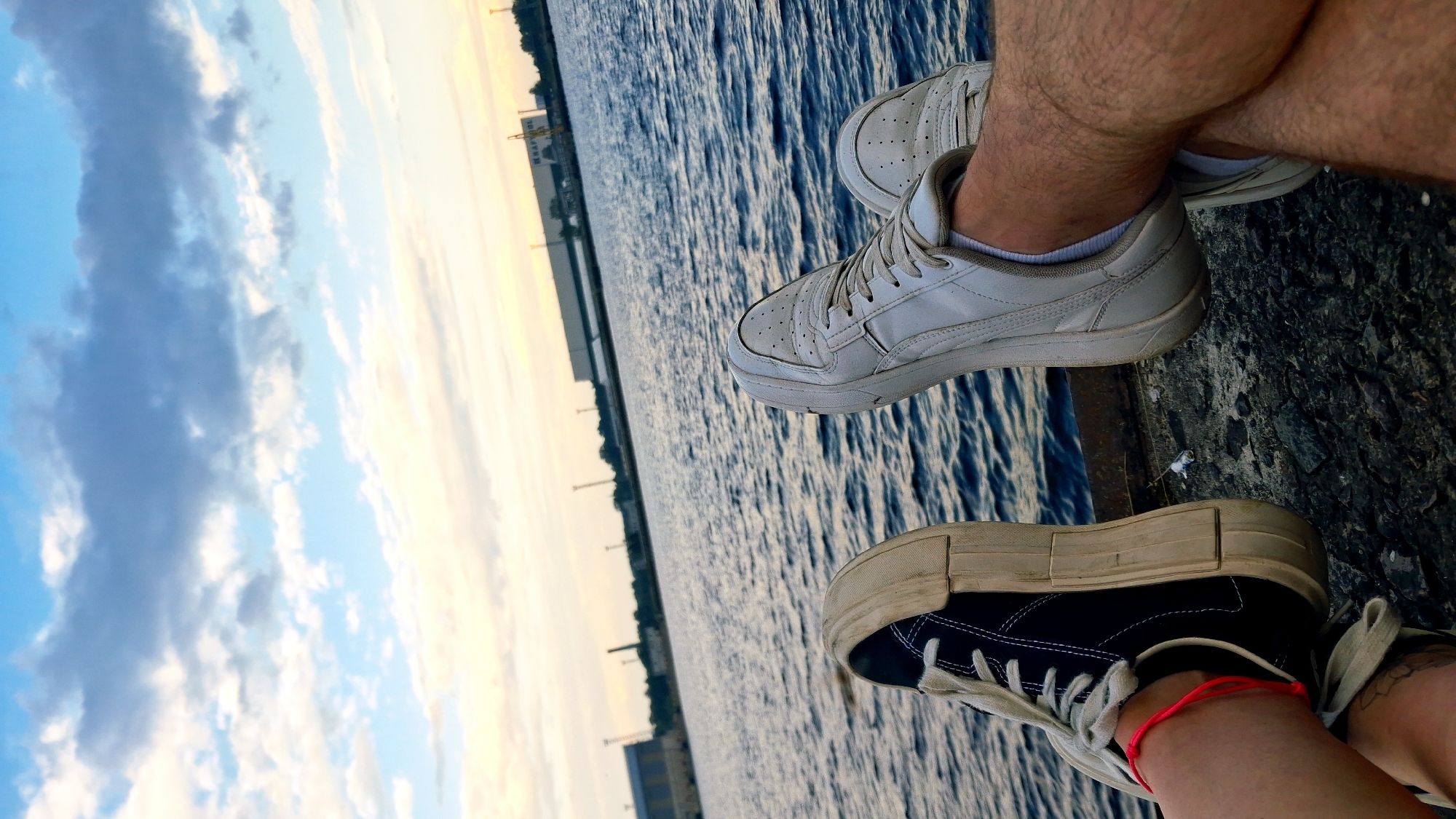 Legs over the edge at a Riga waterfront, summer afternoon