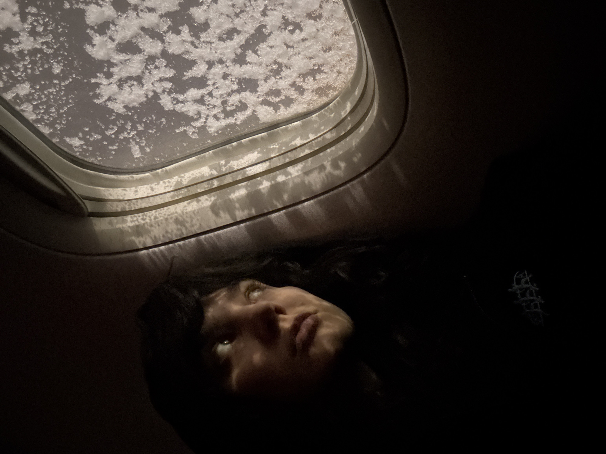 Passenger observes frosted airplane window during flight over Russia
