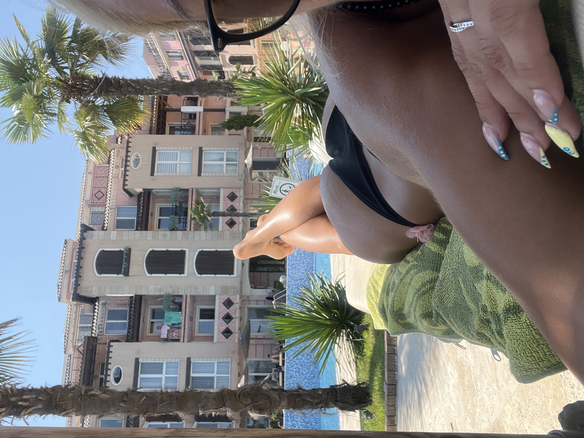 Poolside lounging in a black bikini, sun on feet