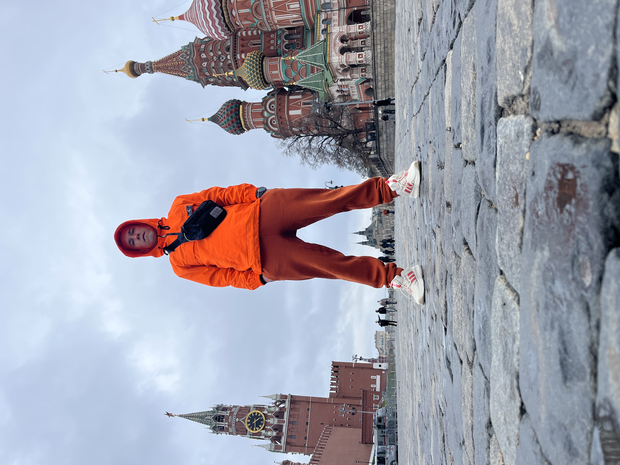 Tourist in orange outfit poses at Moscow's Red Square