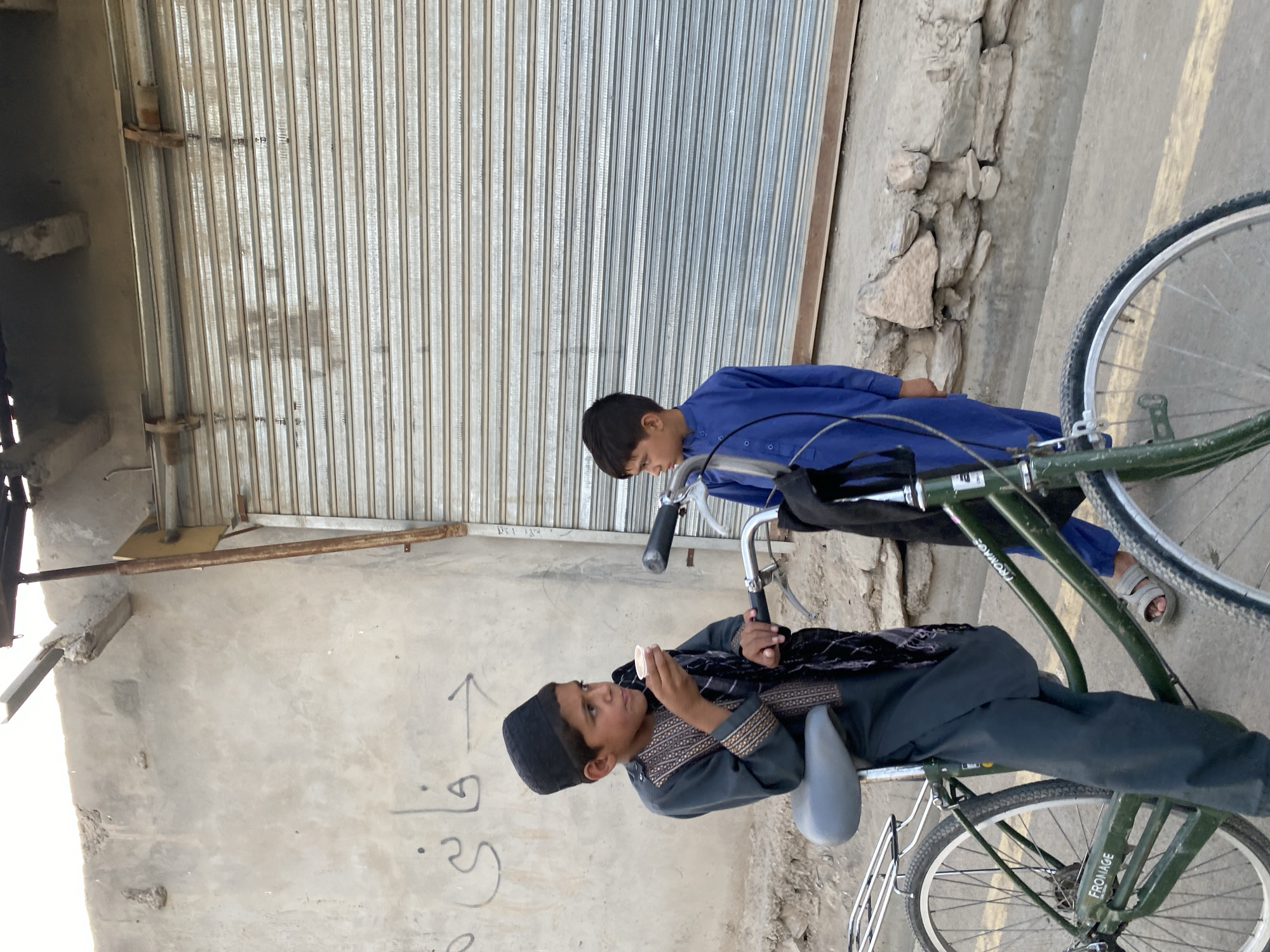 Street scene near shuttered shops in Kandahar, bicycles and traditional dress