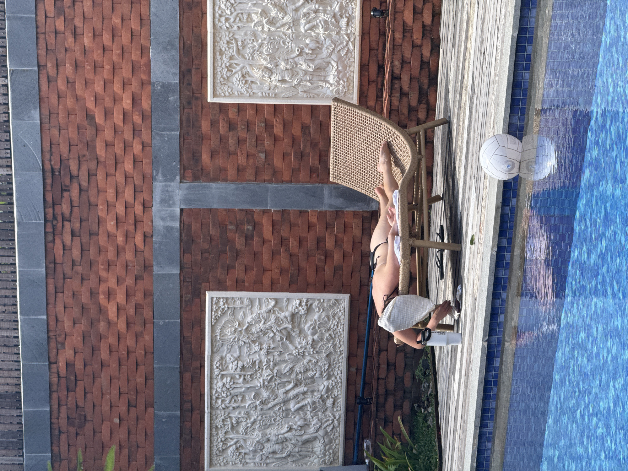 Woman sunbathes poolside in early morning North Kuta