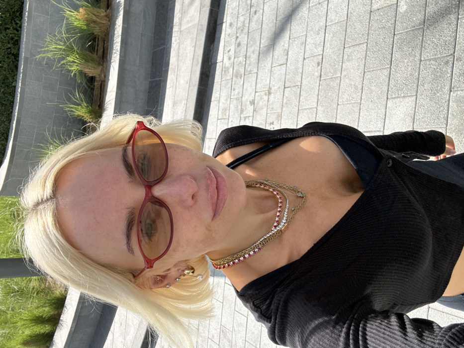 Woman takes outdoor selfie in Dubai wearing red sunglasses