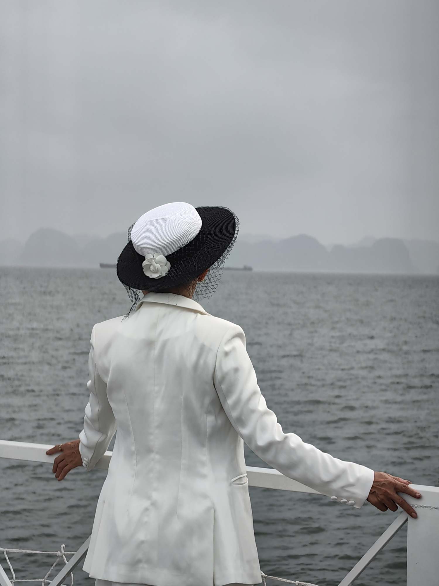 Woman in white contemplates water view from boat deck