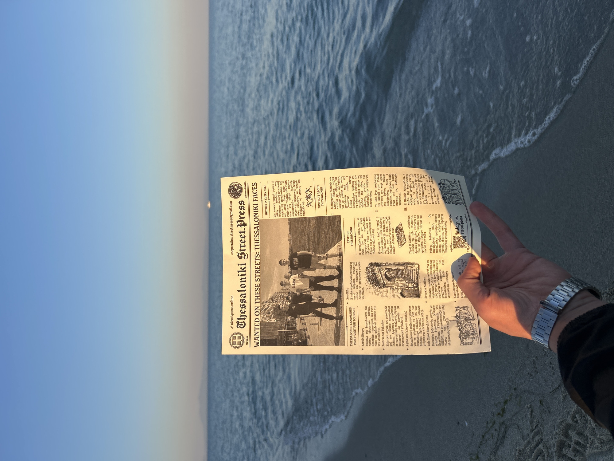 Person reads newspaper at Greek beach during evening hours