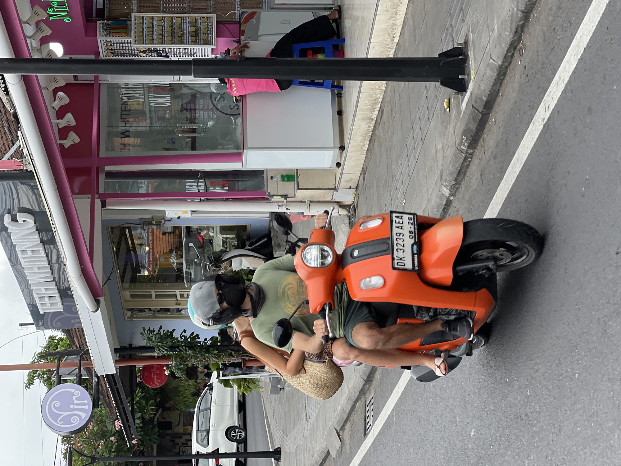 Morning scooter traffic flows past Icon Bali mall in Denpasar
