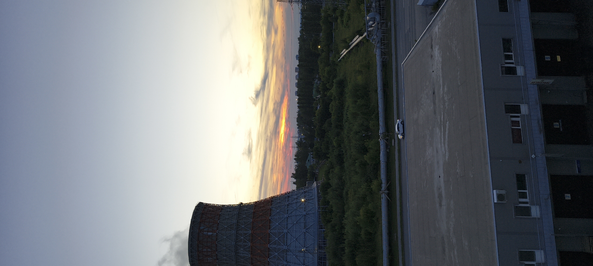Industrial city at golden hour, street life and cooling towers