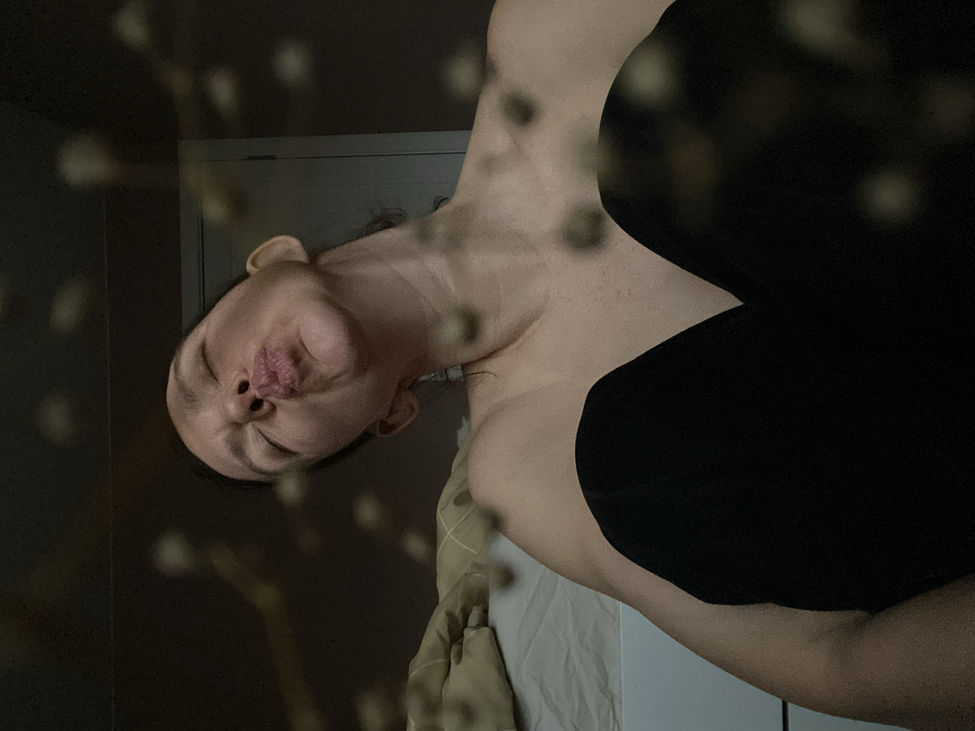 Woman poses on bed in dimly lit bedroom, Chaikovsky