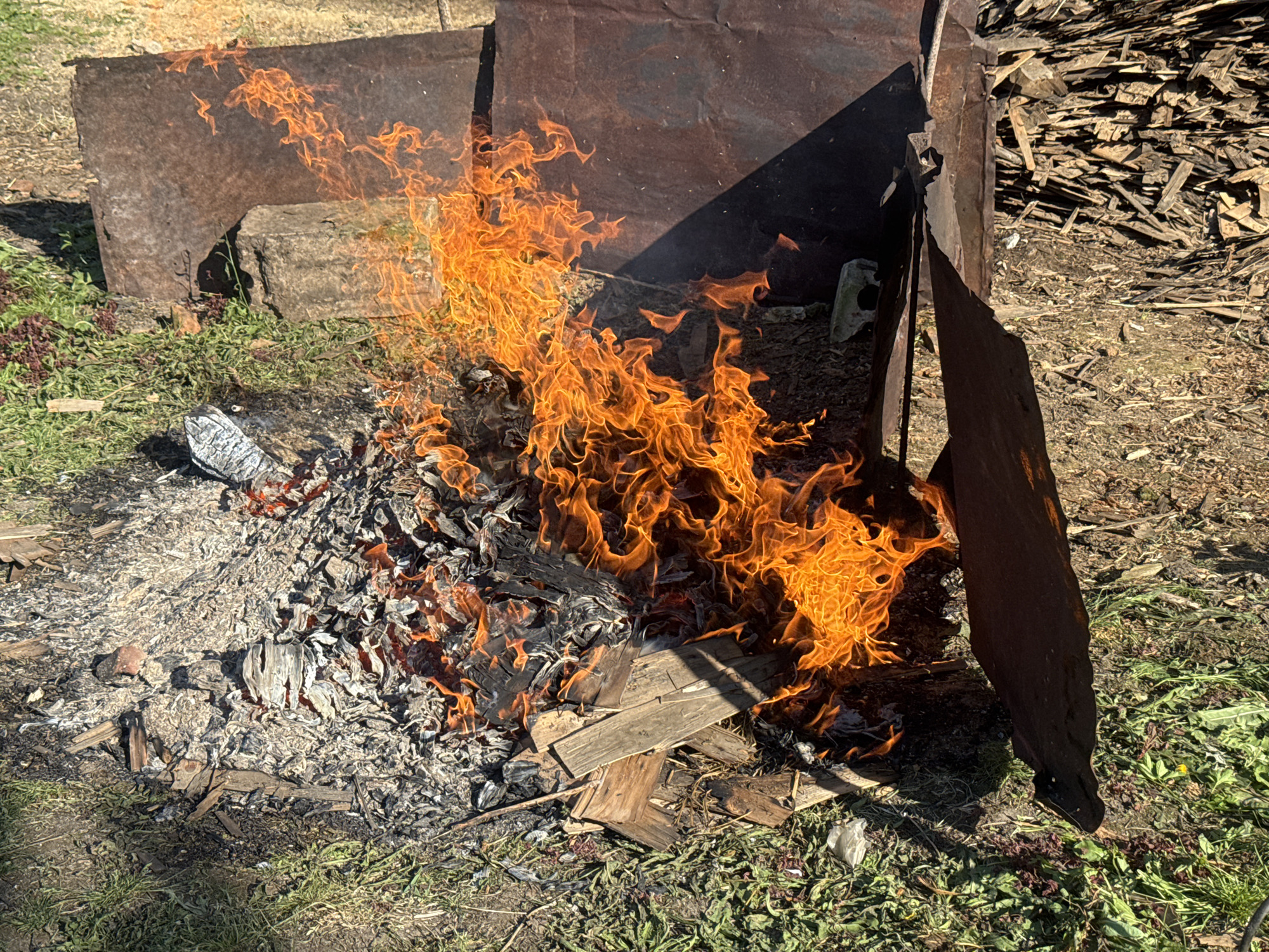 Open fire burns through debris in a rural outdoor setting