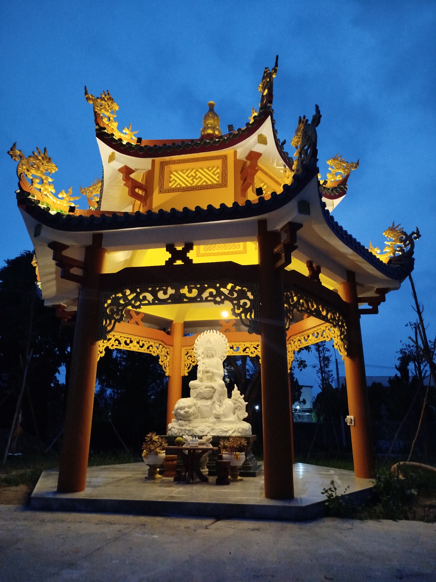White Buddha statue observed in illuminated Vietnamese temple pavilion