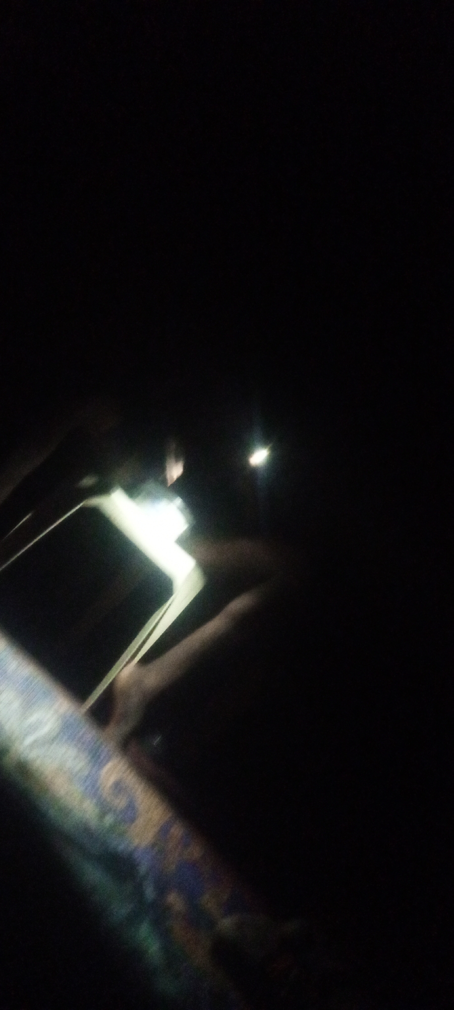 Person reads book by phone light in darkness