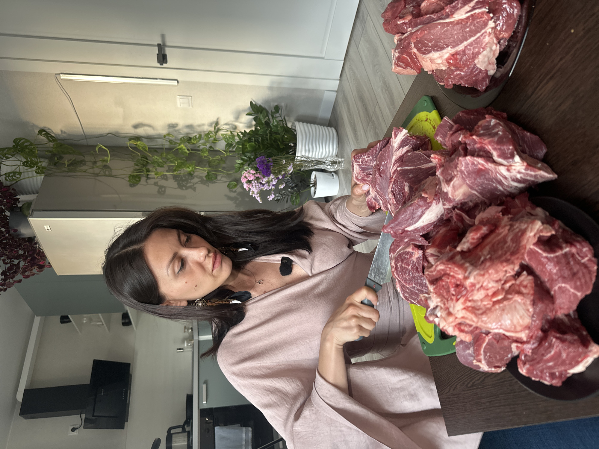 Woman prepares large meat portions in Sinyavino kitchen