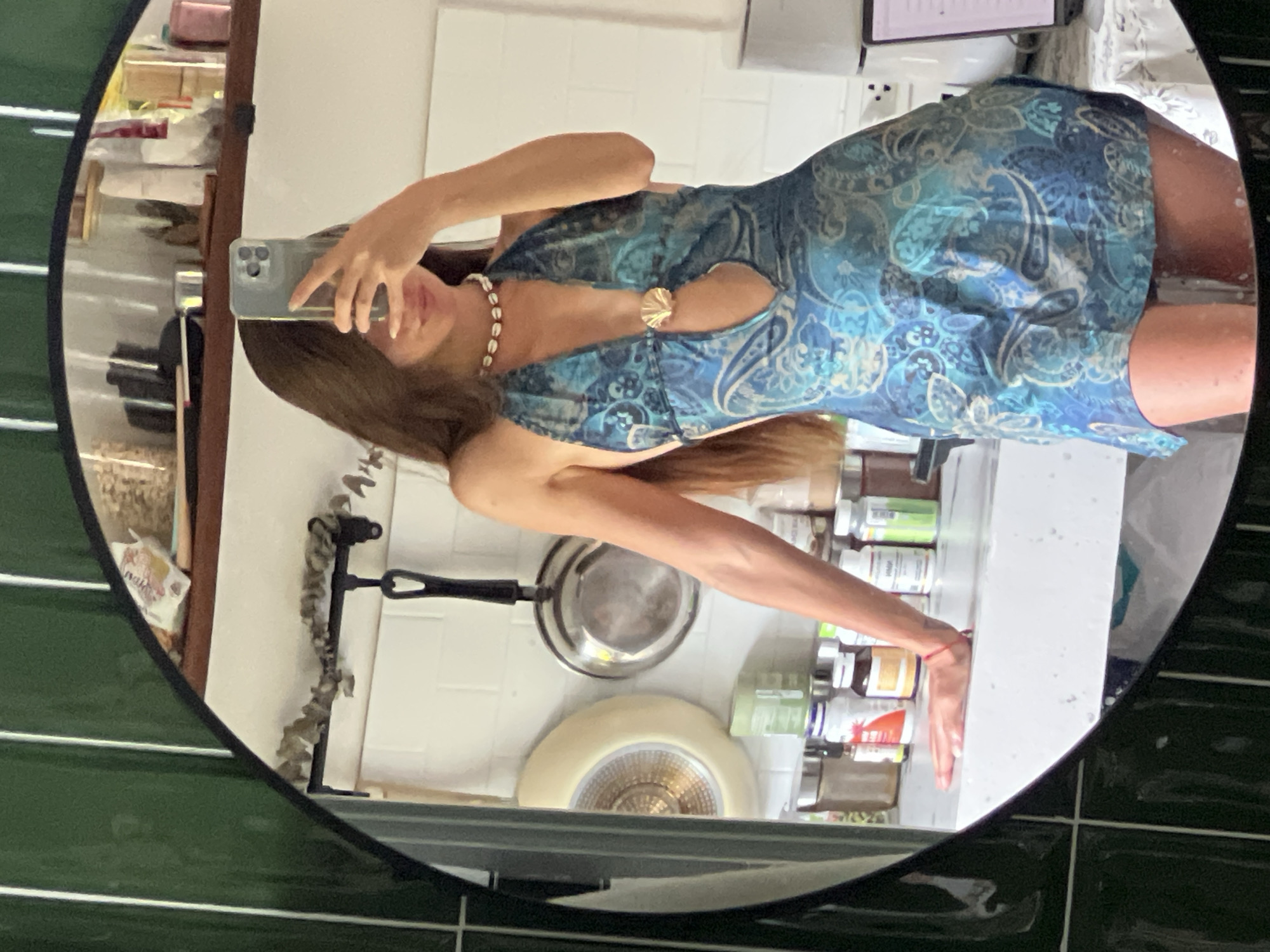 Woman takes mirror selfies in patterned dress indoors