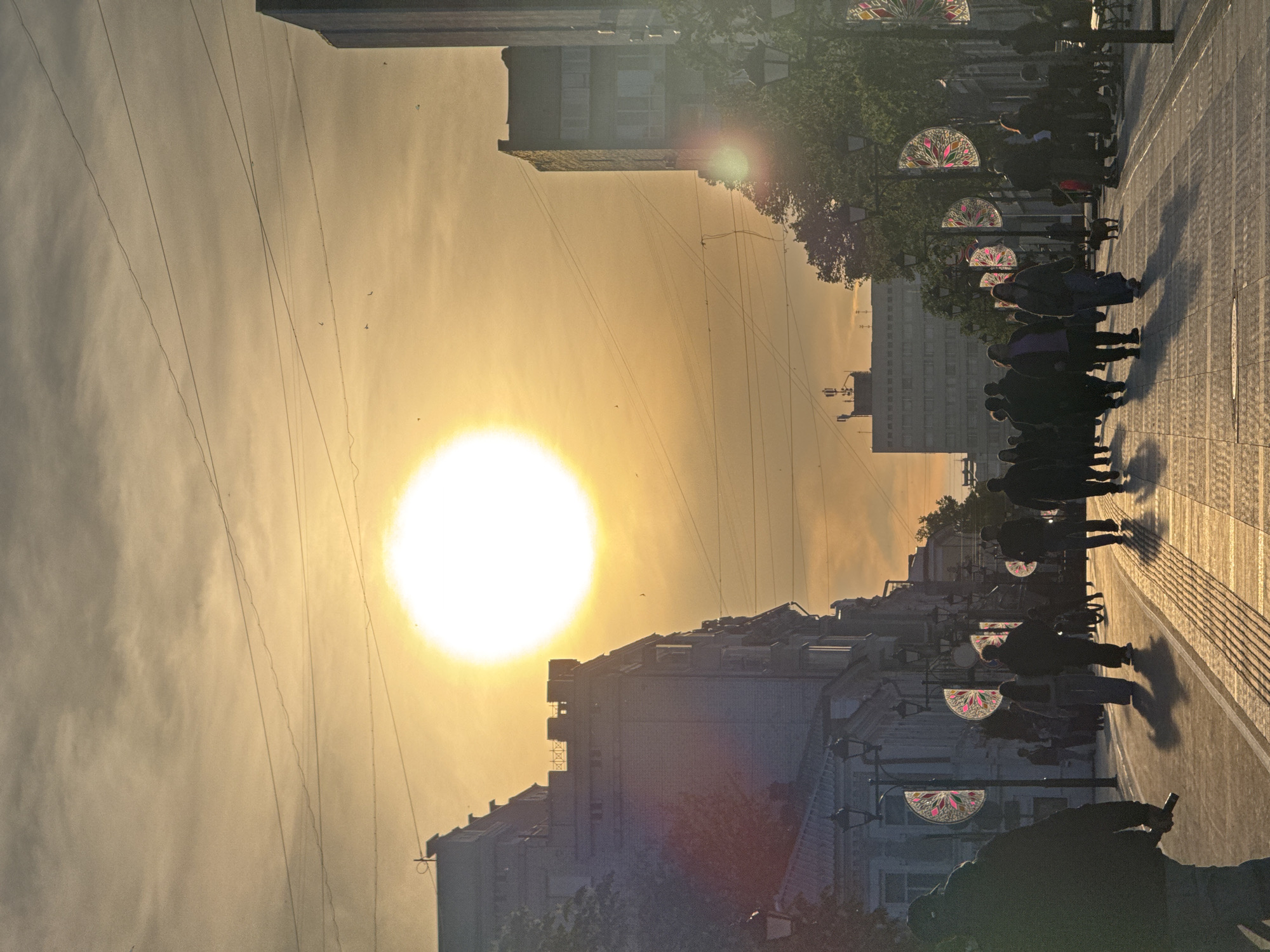 Pedestrians walk Saratov street during golden hour sunset