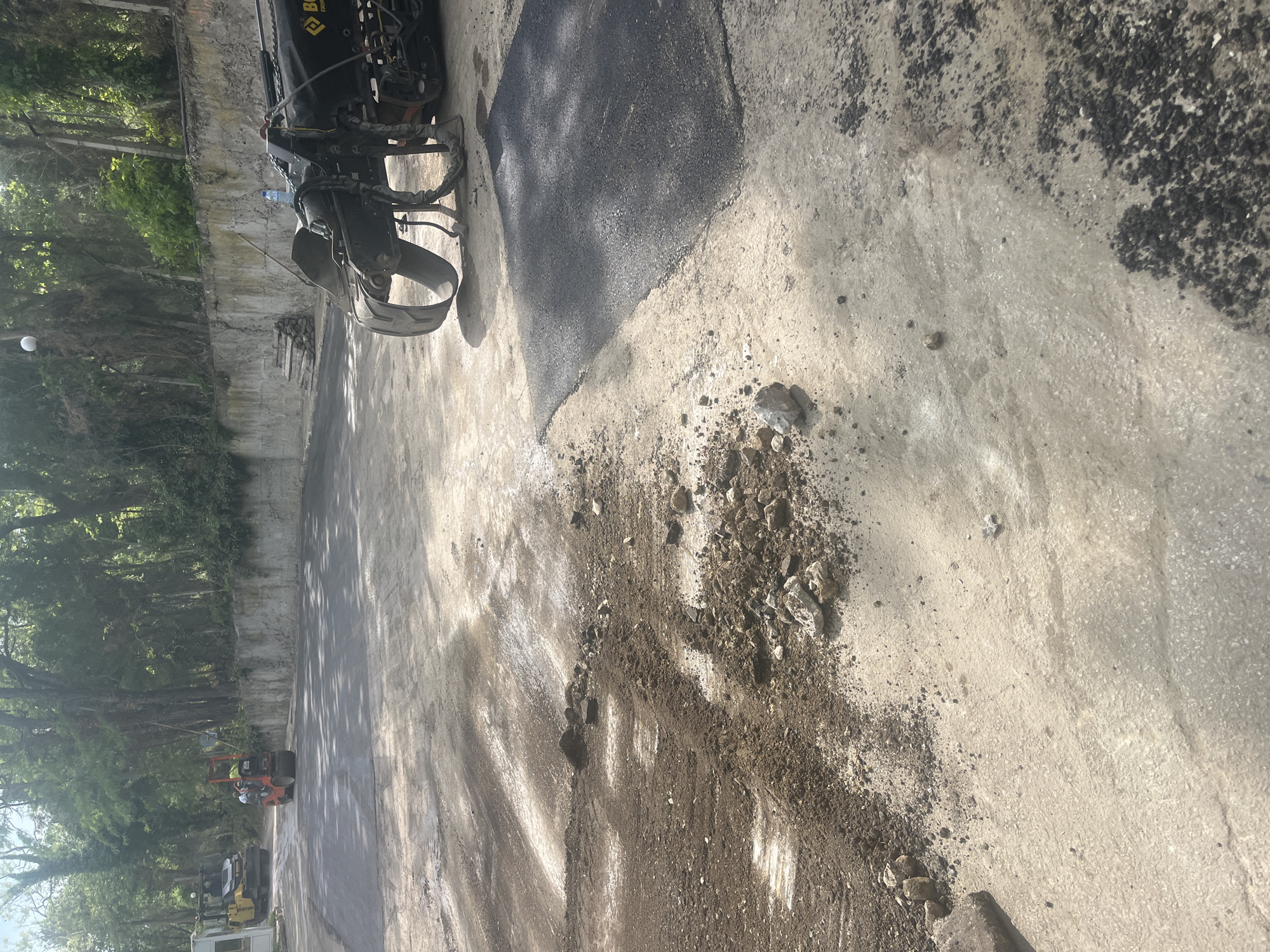 Urban street repair crews operate heavy equipment during asphalt work