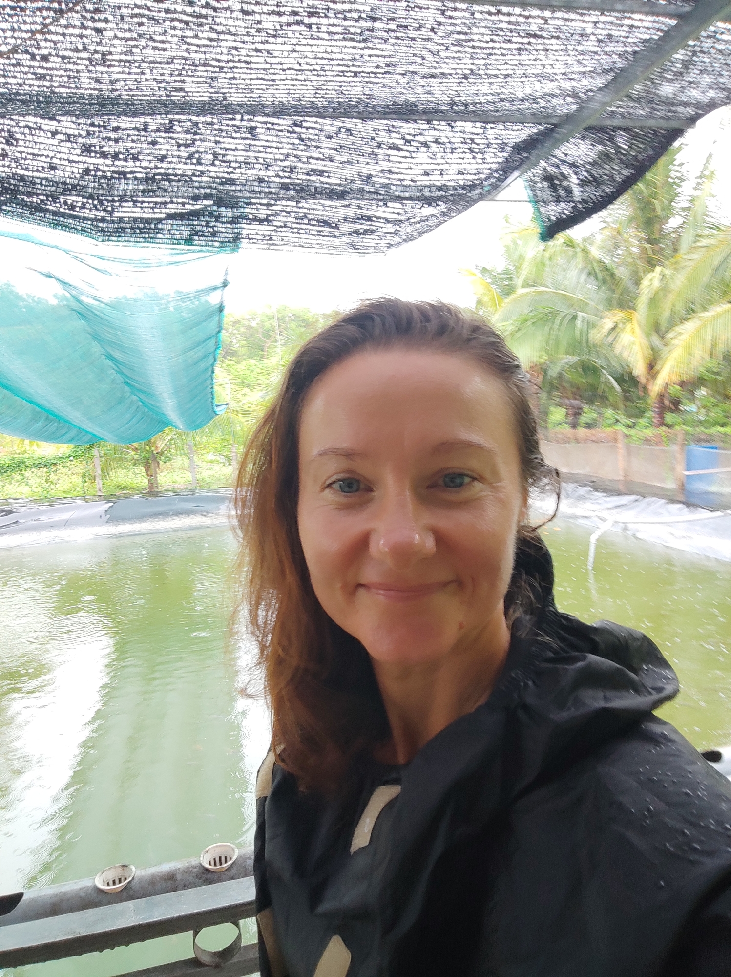 Woman with red mug observed in rainy tropical garden